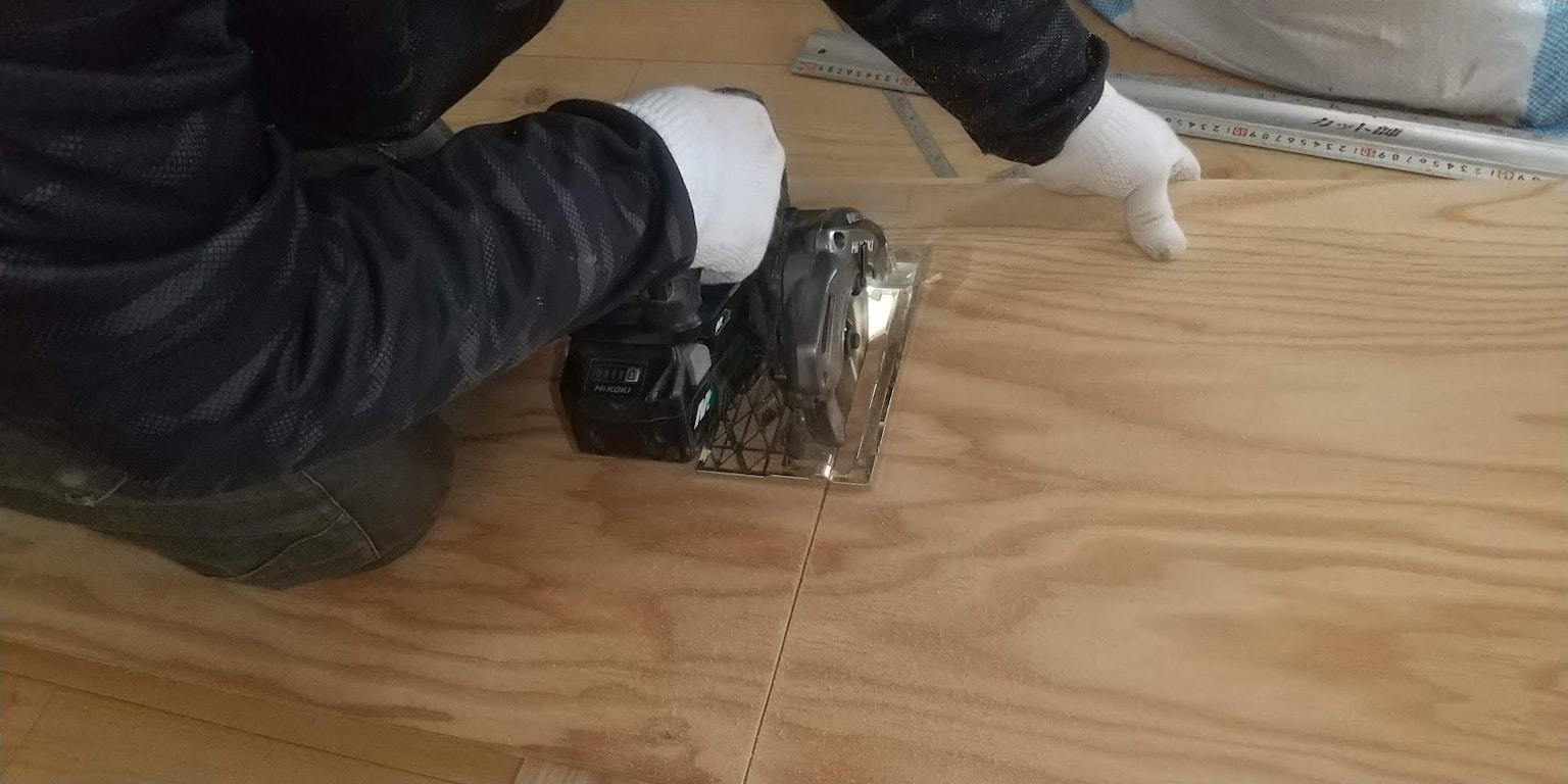Lavoratore che installa pavimenti in legno usando attrezzi indossando guanti