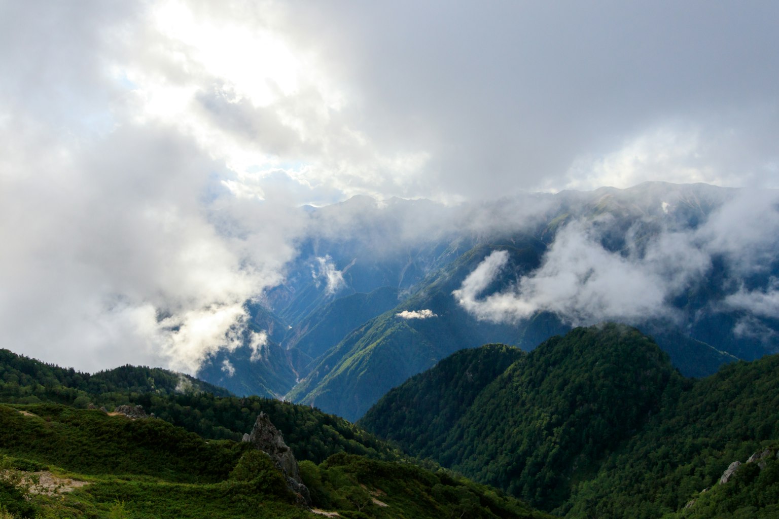 雲に覆われた山々の景色 緑の丘と谷の間に広がる壮大な風景