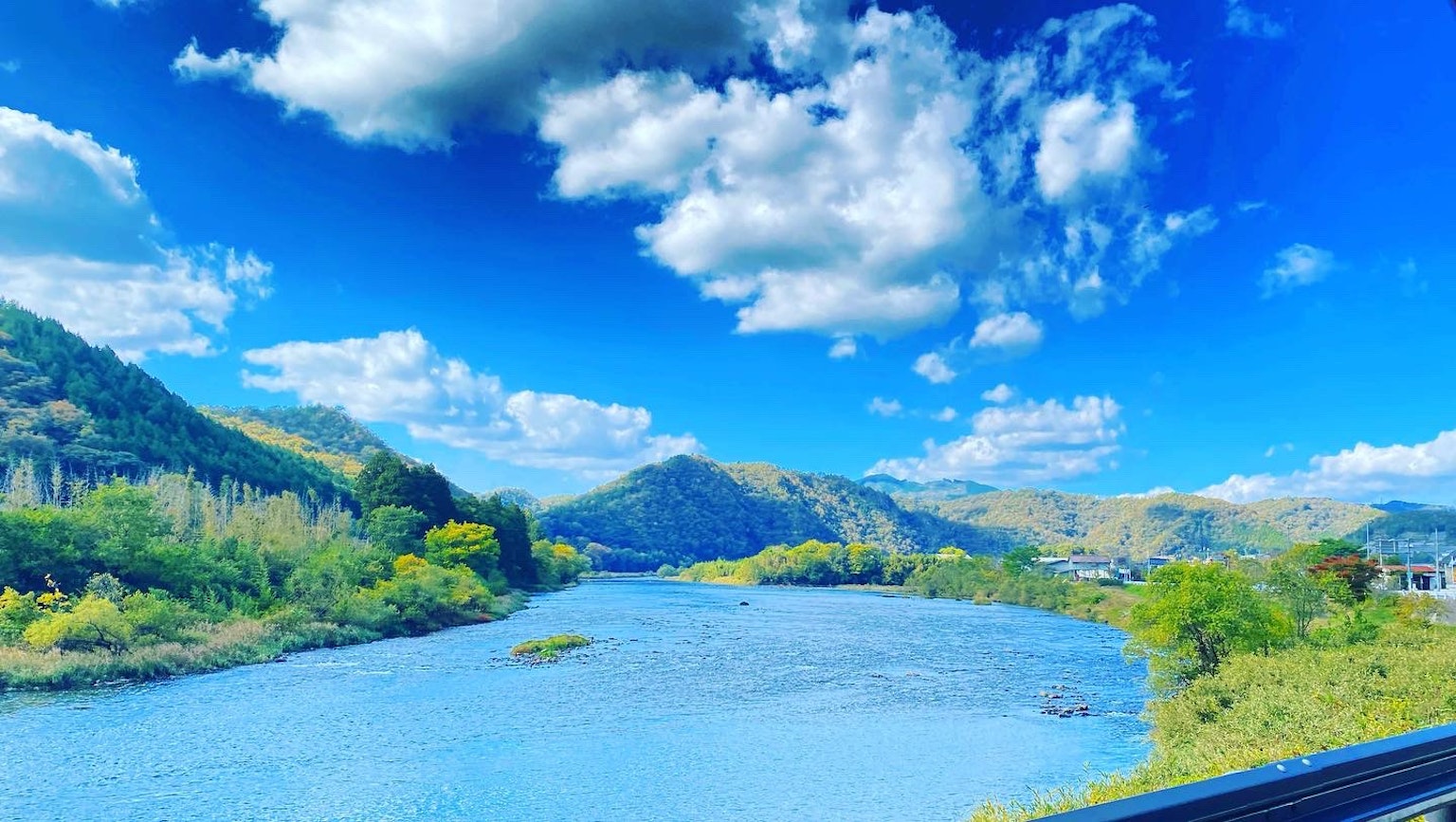 Paysage de rivière pittoresque avec ciel bleu et nuages entouré de collines verdoyantes