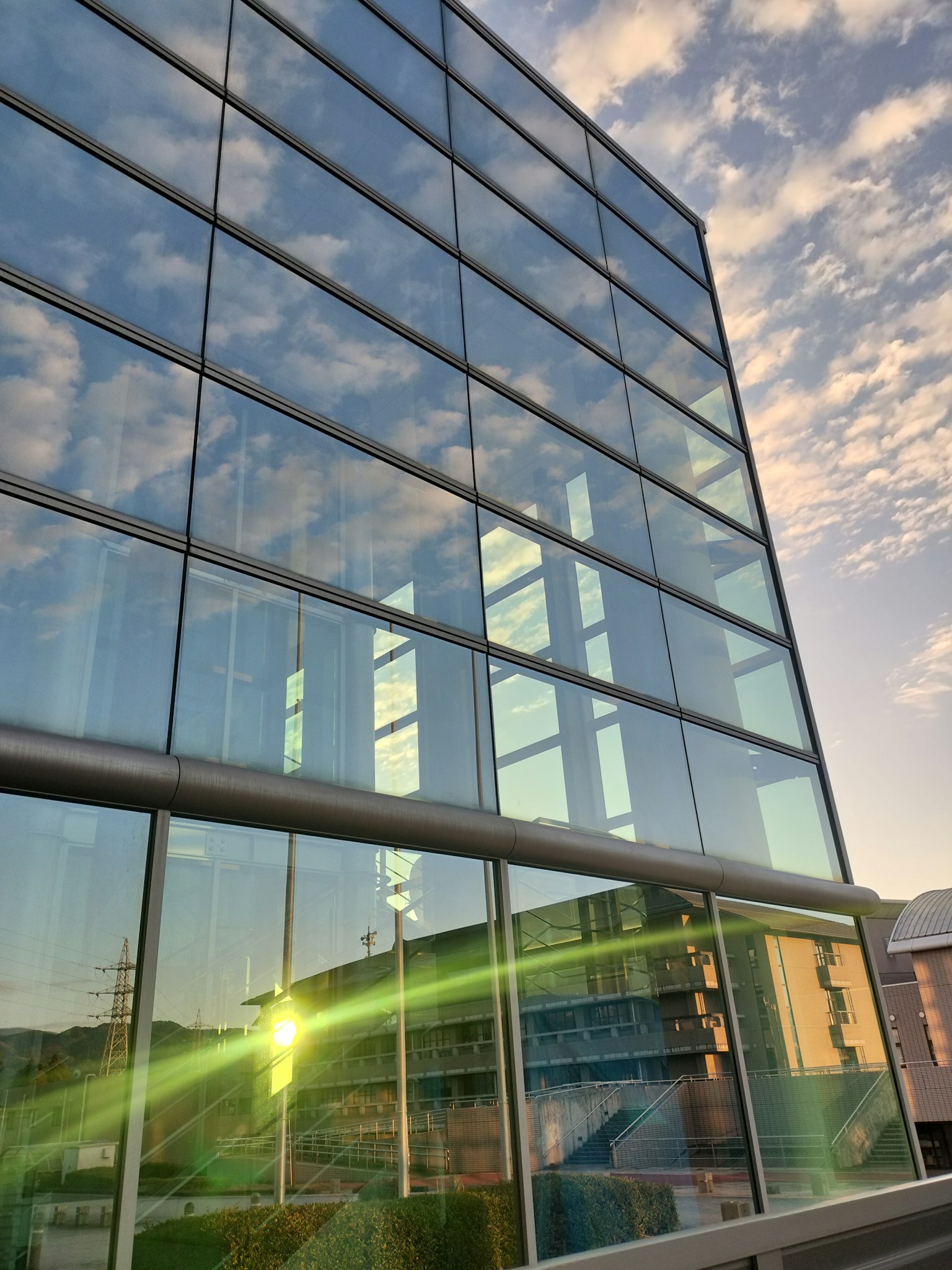 Façade moderne en verre reflétant le ciel du coucher de soleil