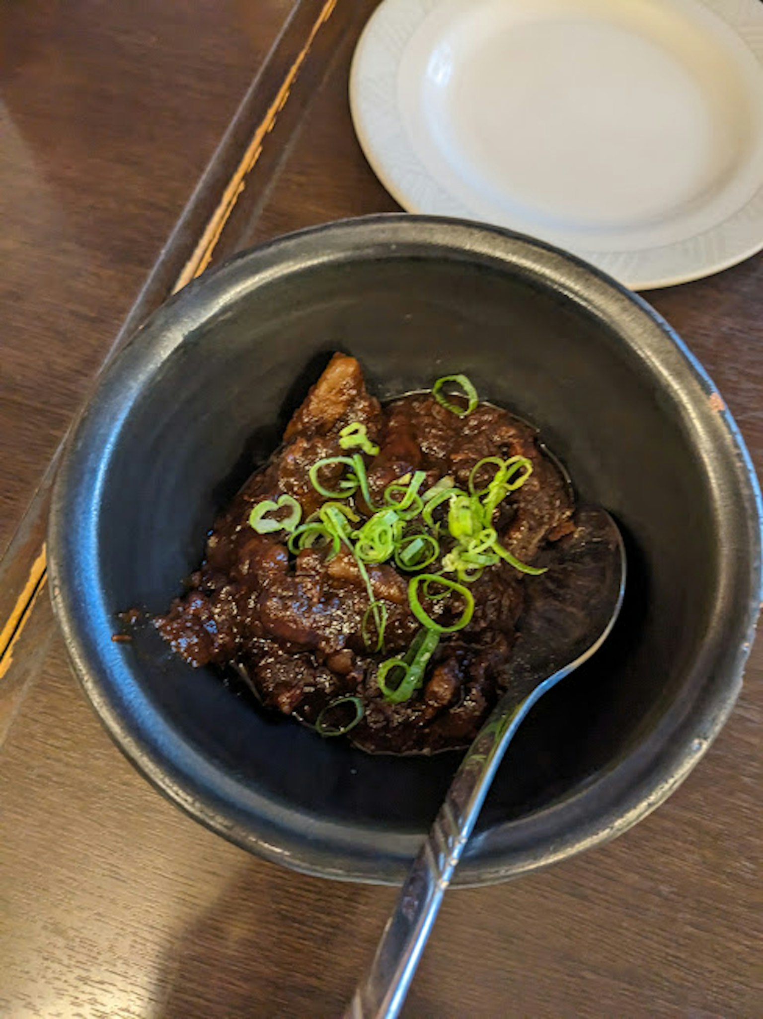 黑碗中的菜肴上放有青葱