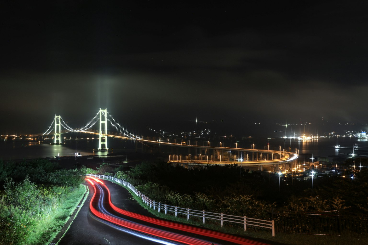 Puente Akashi Kaikyō de noche con estelas de luz de coches