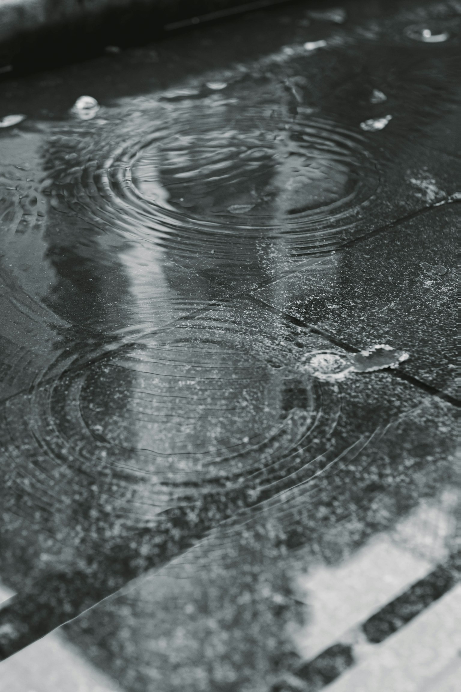 Des gouttes de pluie créant des ondulations sur une surface en pierre