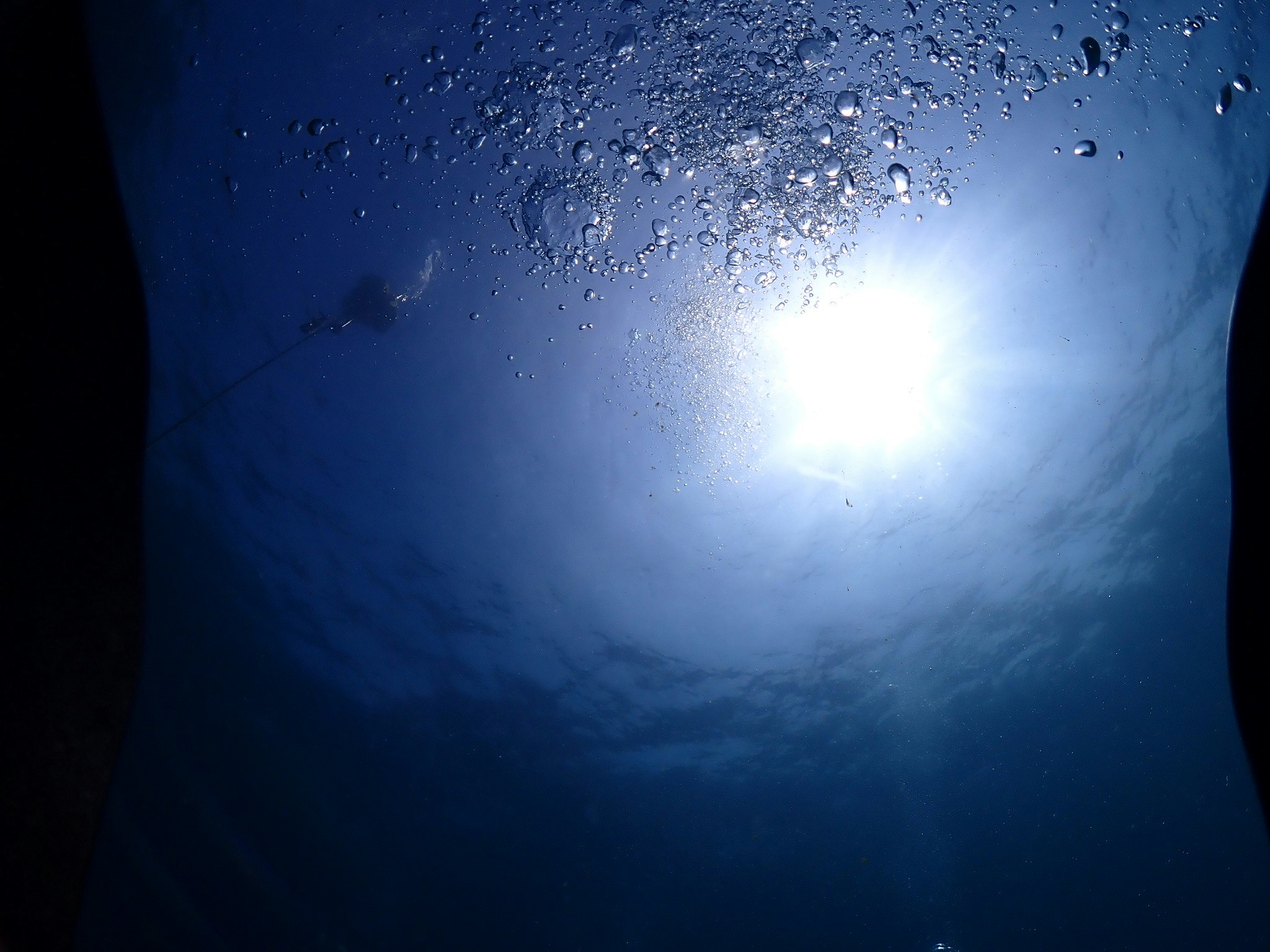 希望の光が差し込む海中の泡と太陽光のきらめき