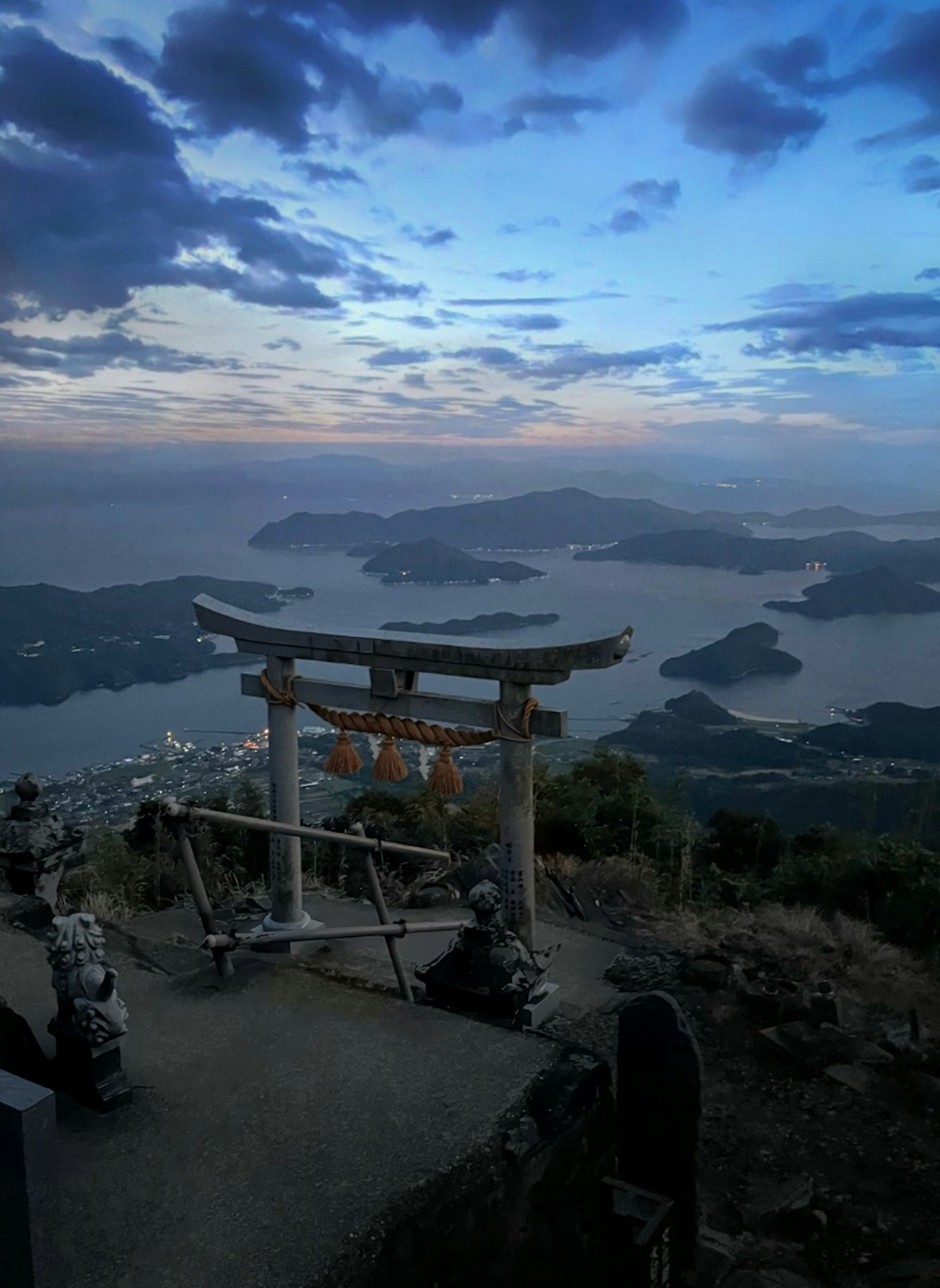 Panoramablick von einem Berggipfel mit einem Torii, das auf das Meer blickt