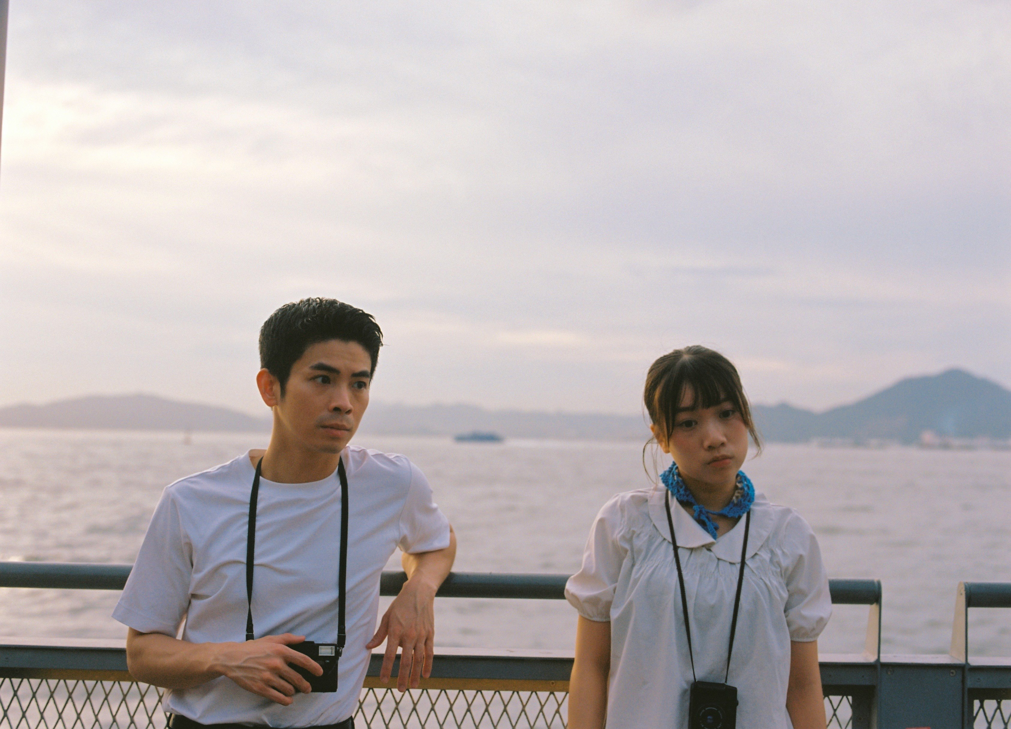 海辺の展望デッキで並ぶ2人の人物