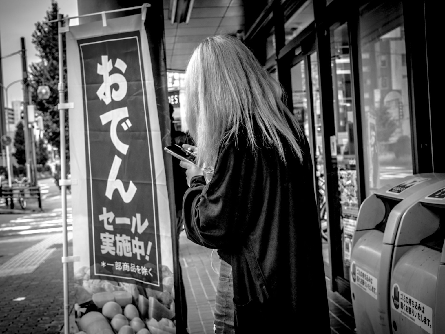 Una donna dai lunghi capelli che guarda un'insegna di oden in bianco e nero