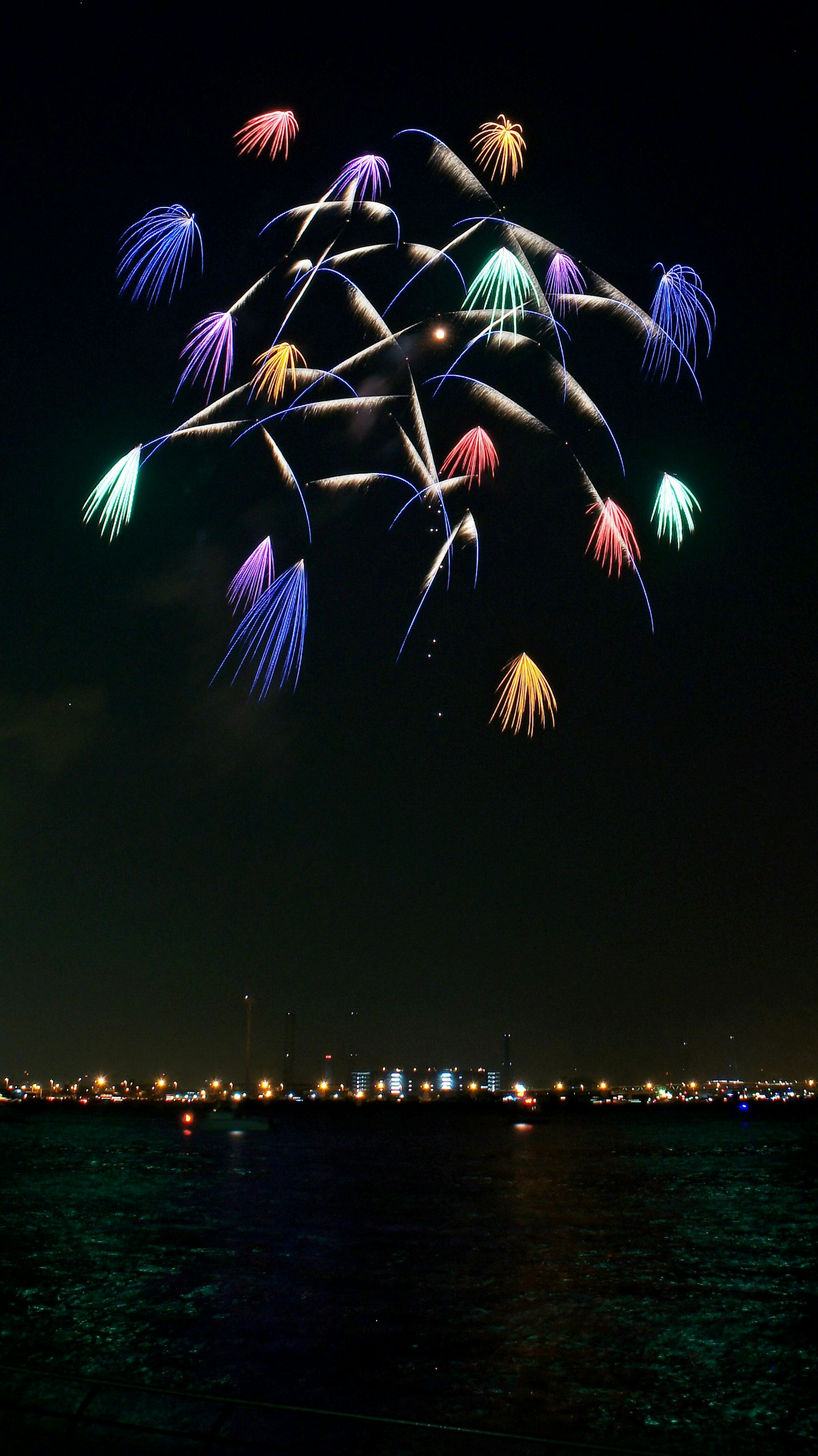 Colorful fireworks blooming in the night sky reflecting on the water