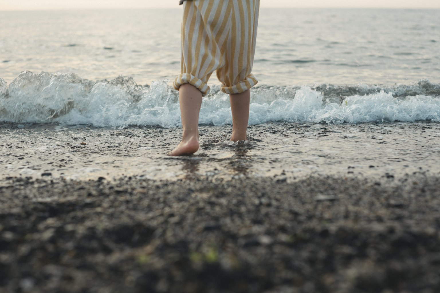 孩子站在海邊，海浪拍打