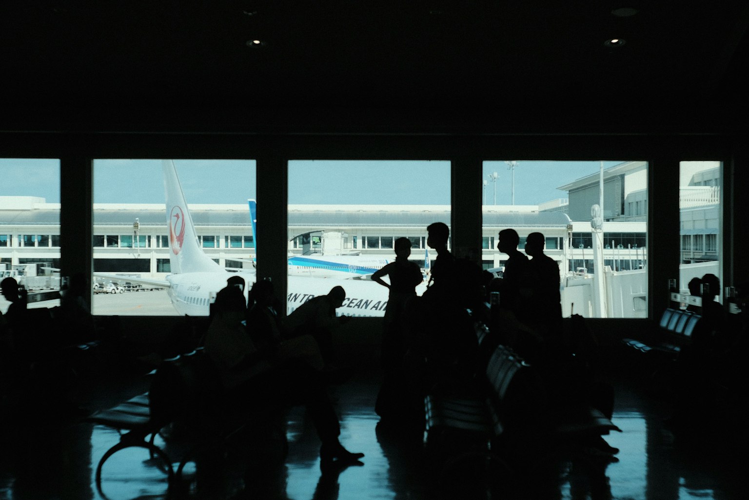 공항 터미널에서 비행기를 바라보는 사람들의 실루엣