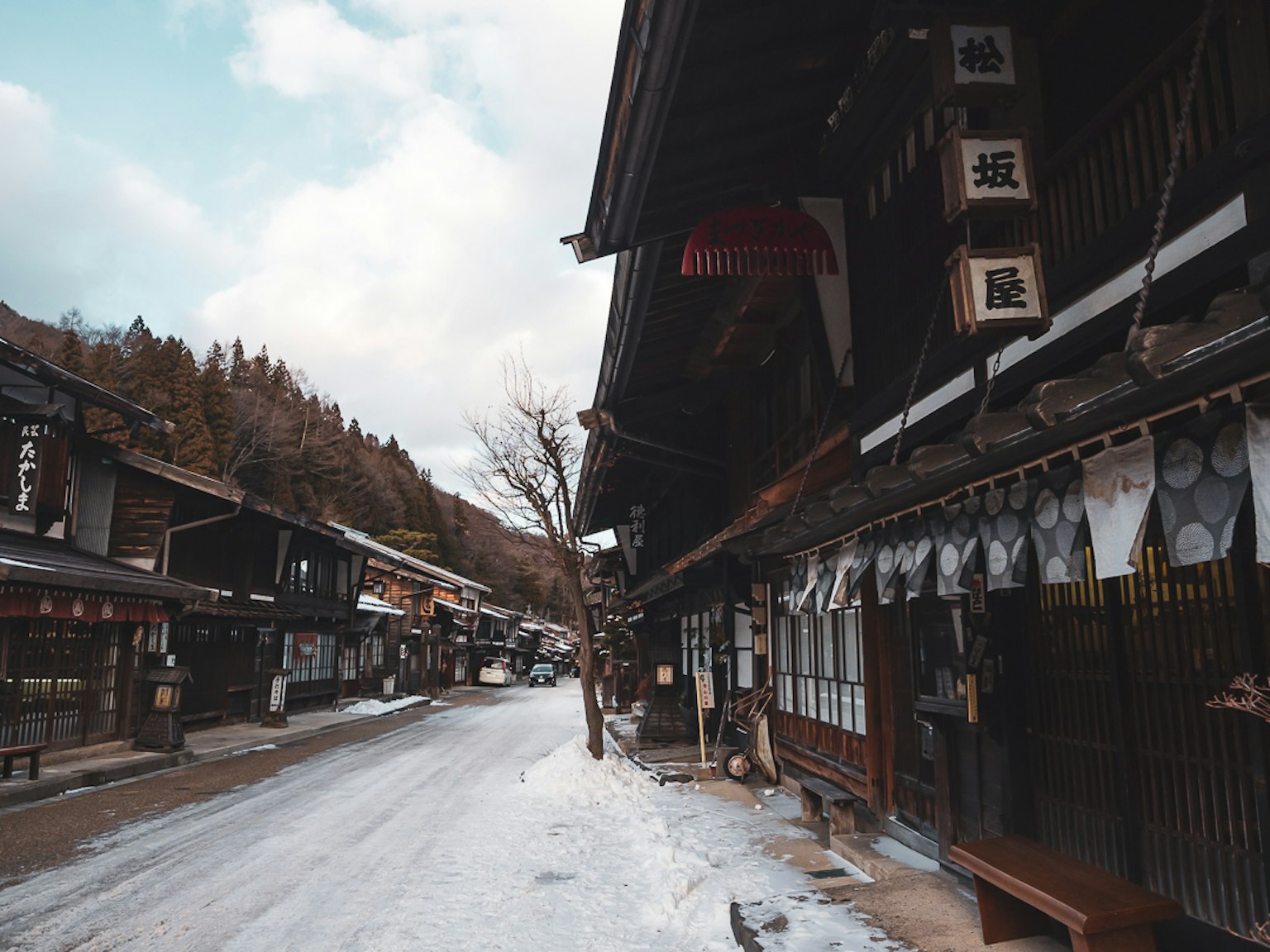 Snowy street scene featuring traditional buildings and shops