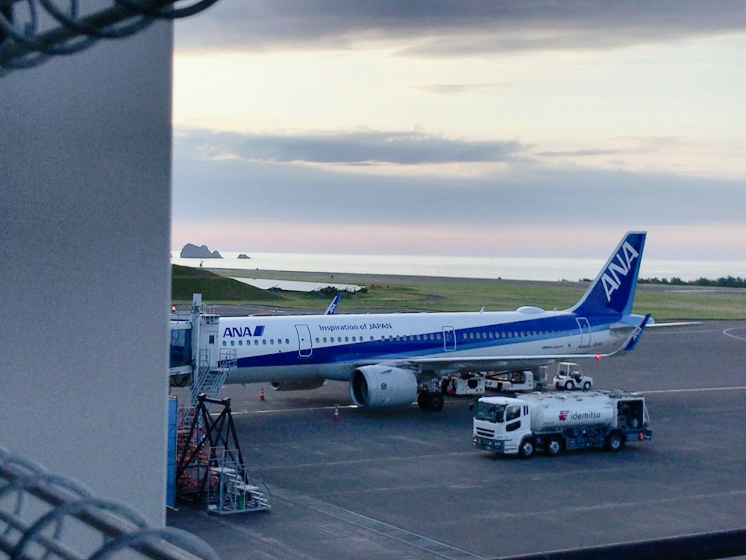 Avion de passagers ANA garé à l'aéroport avec la mer et des nuages en arrière-plan
