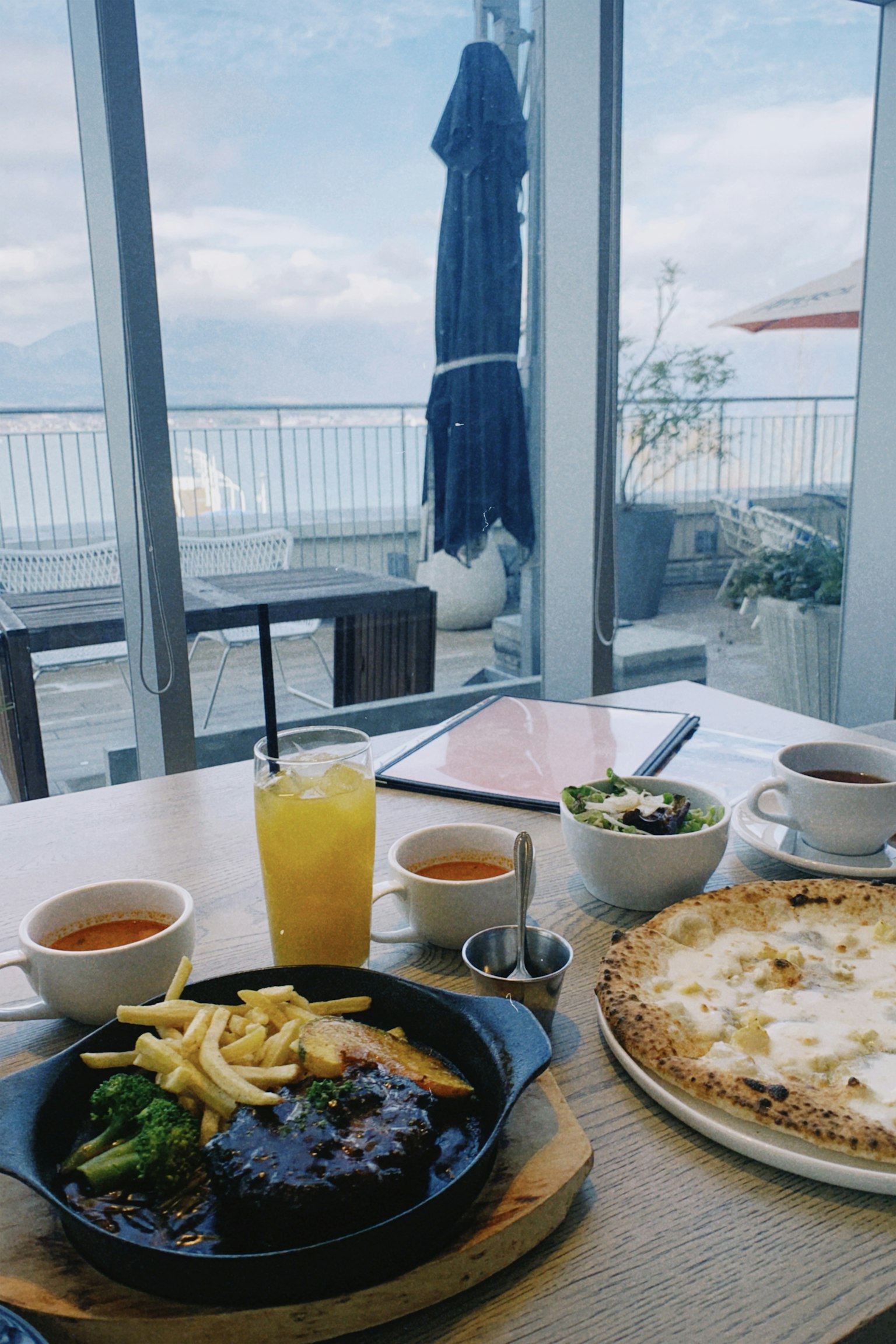 Un ensemble de plats et de boissons sur une table avec une belle vue sur la mer en arrière-plan