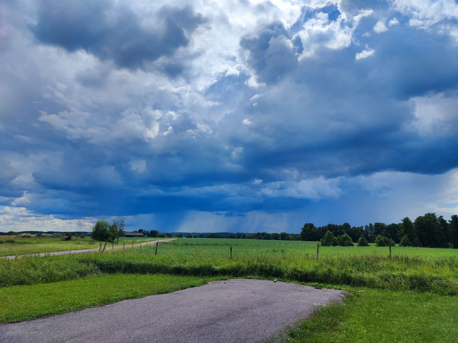 Paysage avec des nuages sombres et un ciel bleu champ de gazon vert et route pavée