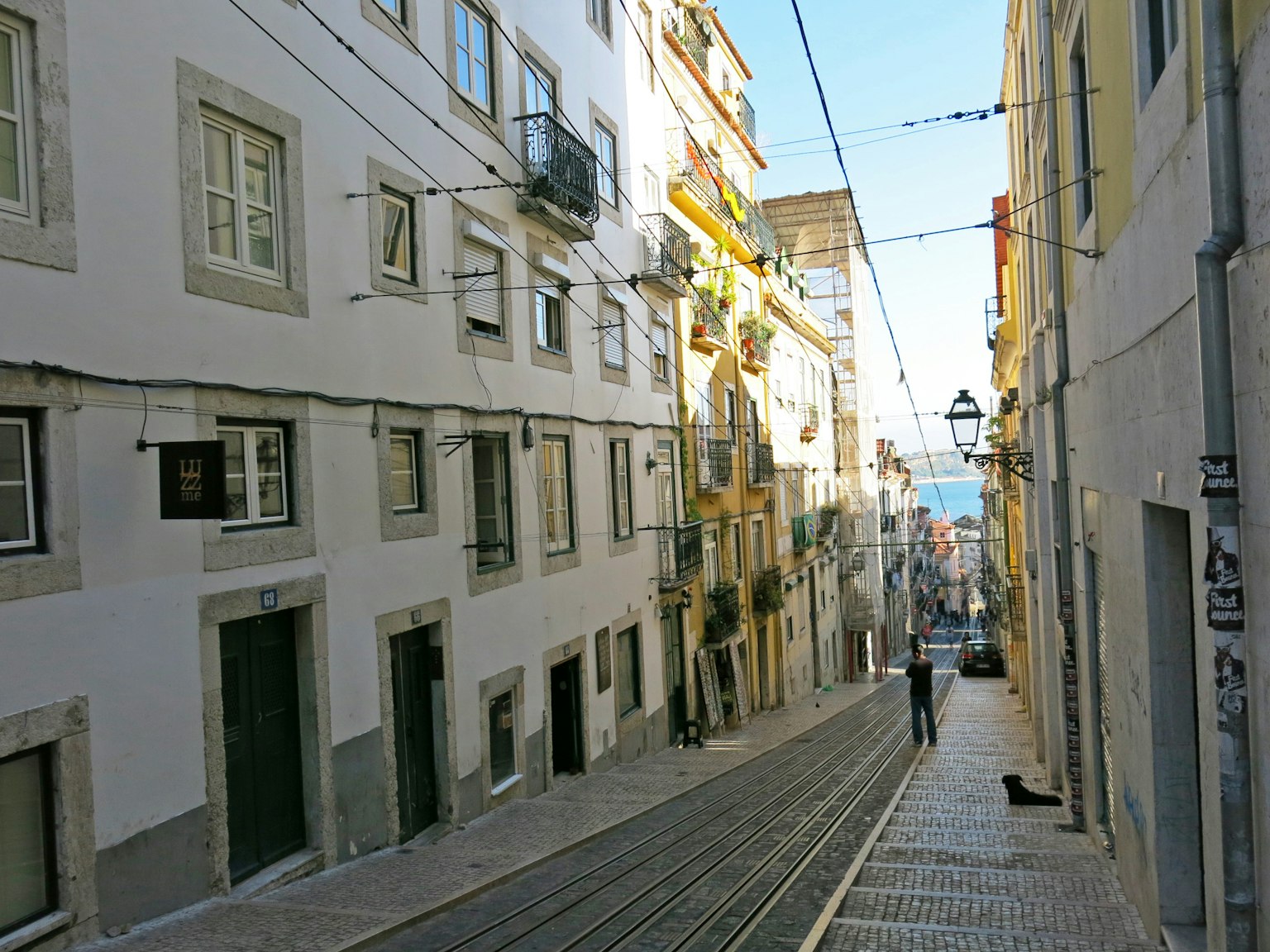 Narrow street in Lisbon with white buildings and tram tracks