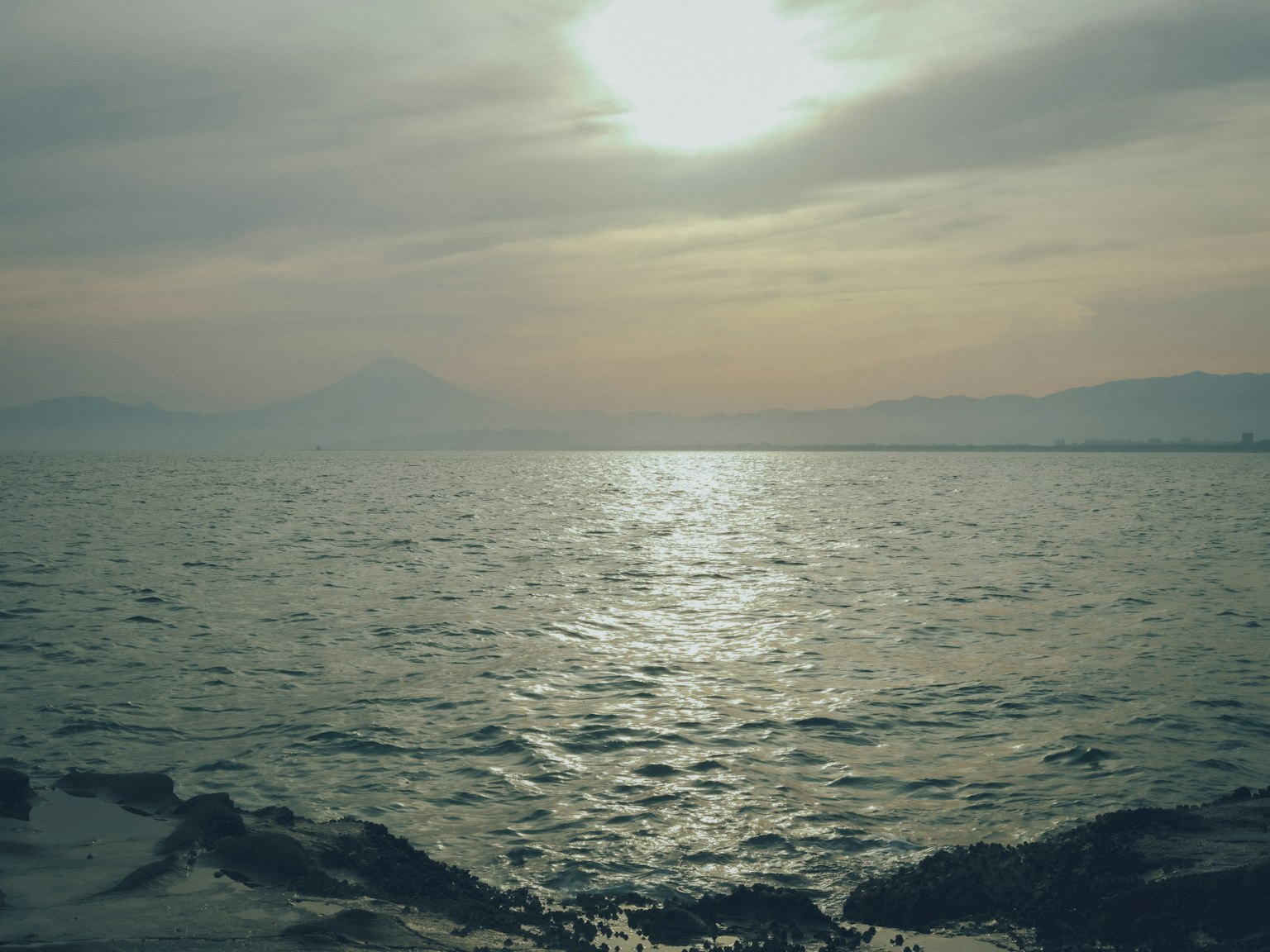 Paesaggio marino sereno con cielo nuvoloso e luce del tramonto che si riflette sull'acqua