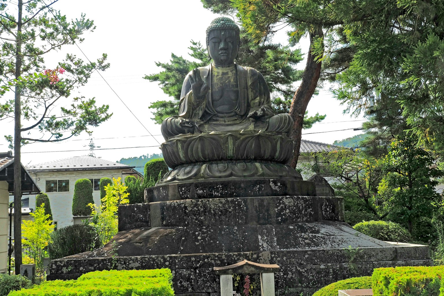 Gran estatua de Buda sentado en un jardín sereno rodeado de vegetación