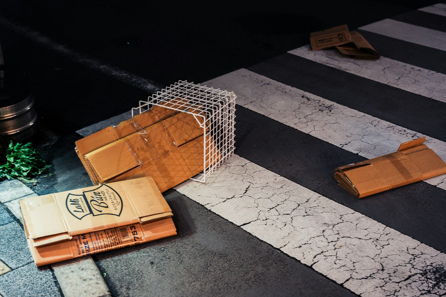Des cartons éparpillés et un panier en métal sur un passage piéton