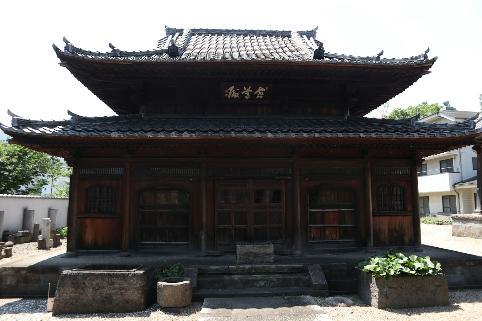 Vista exterior de un templo japonés tradicional de madera con techo de tejas y puertas de madera talladas