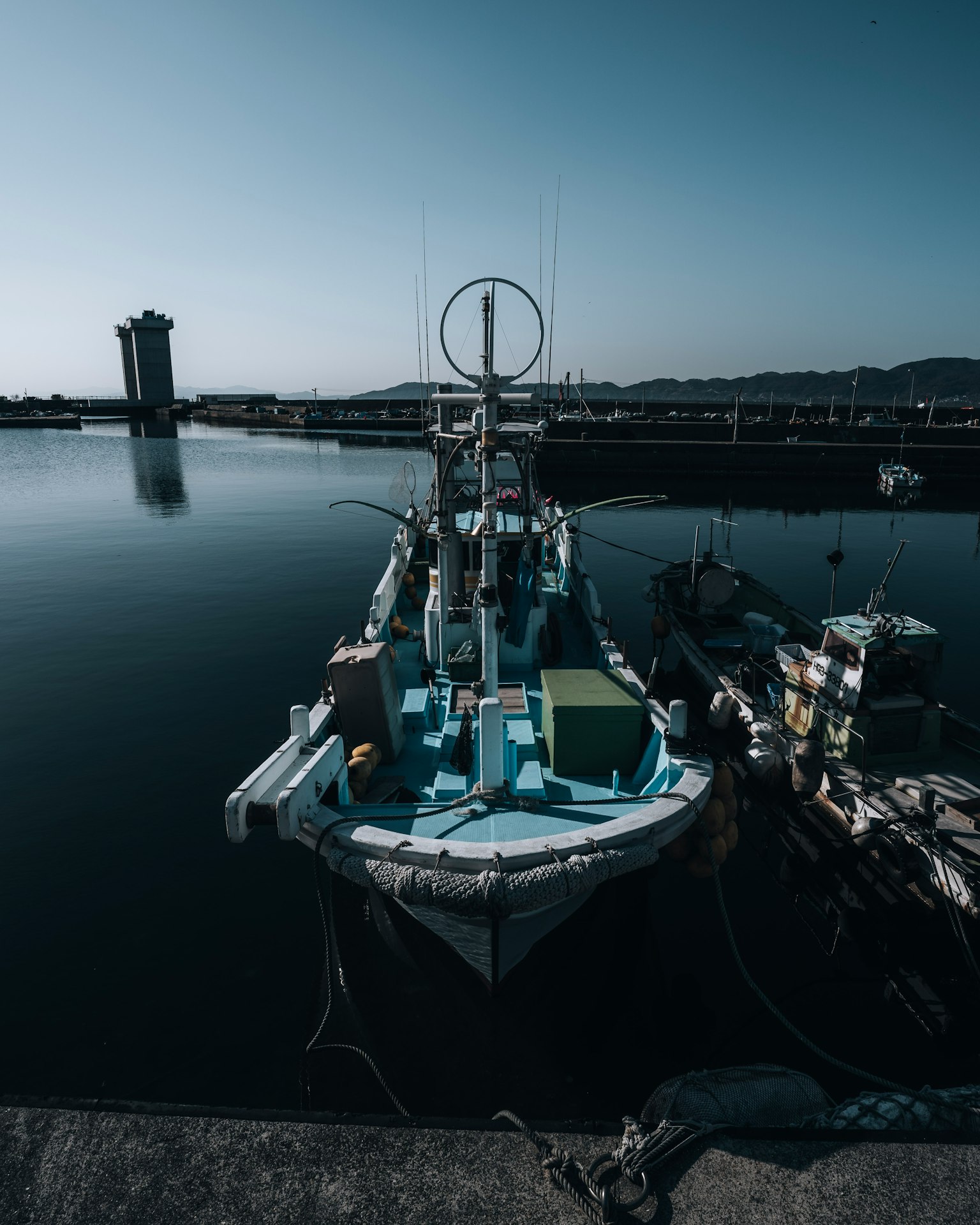 Barco de pesca azul atracado en un puerto tranquilo con un edificio