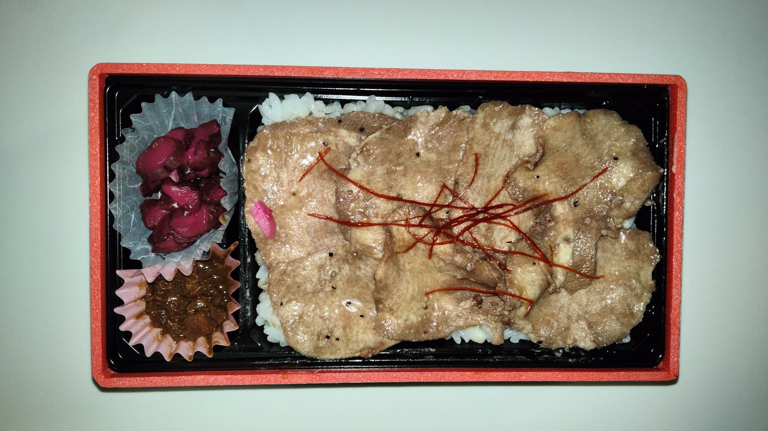 Gambar kotak bento dengan ayam goreng di atas nasi dan lauk berwarna-warni