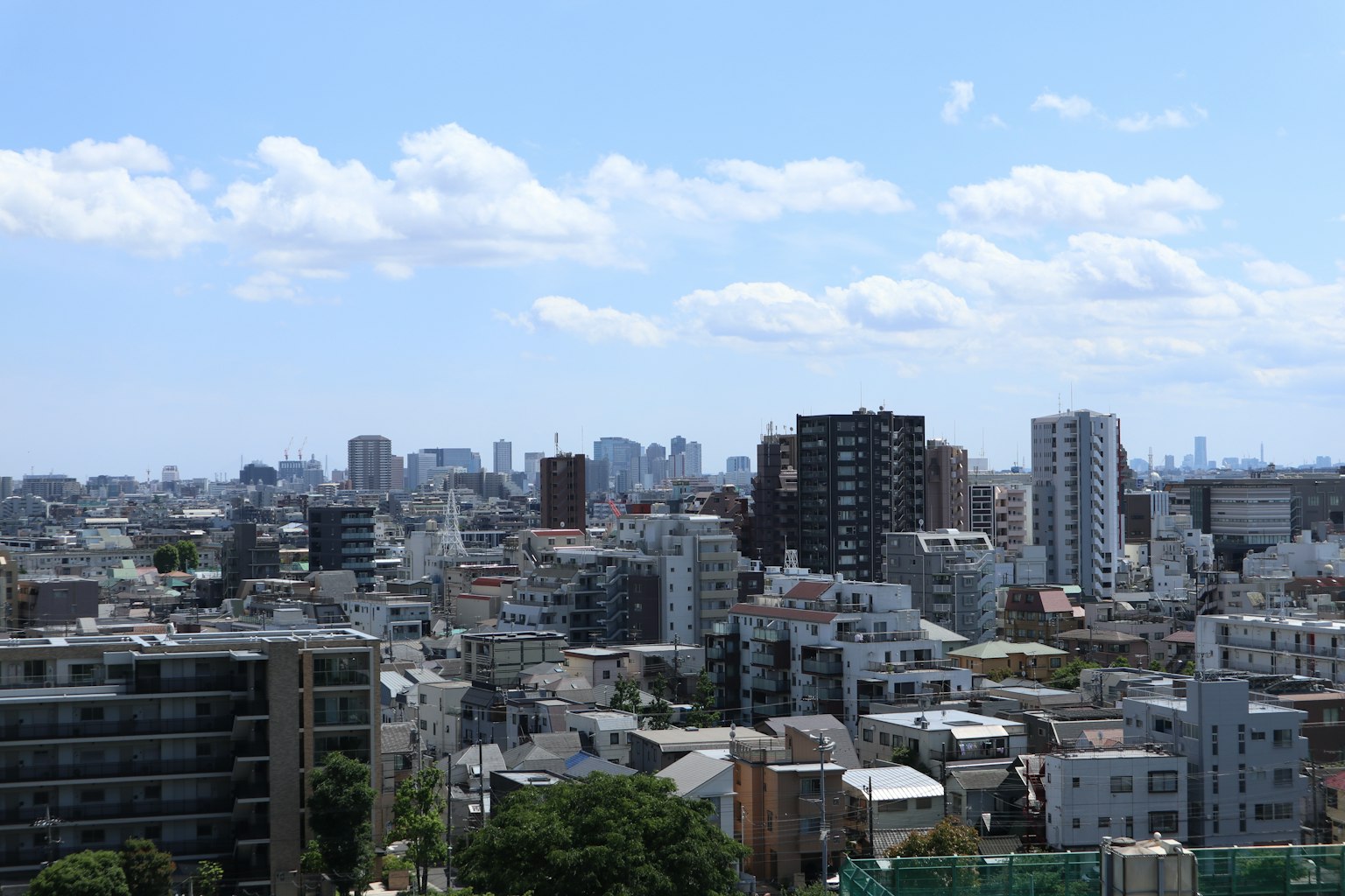 Stadtlandschaft von Tokio mit einer Mischung aus Hochhäusern und Wohngebieten unter einem klaren blauen Himmel