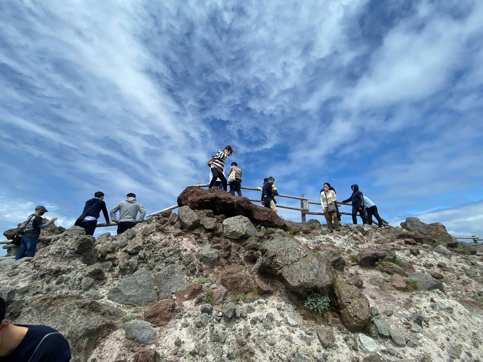 People standing on a rocky summit under a blue sky