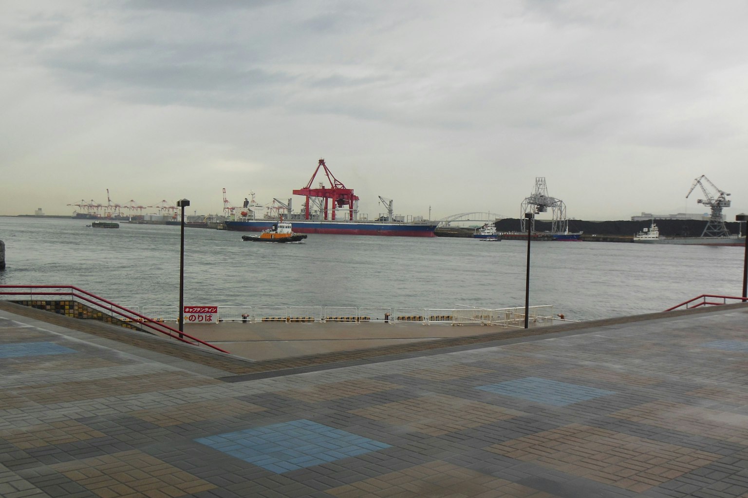Vista del mar y el puerto con barcos y grúas rojas