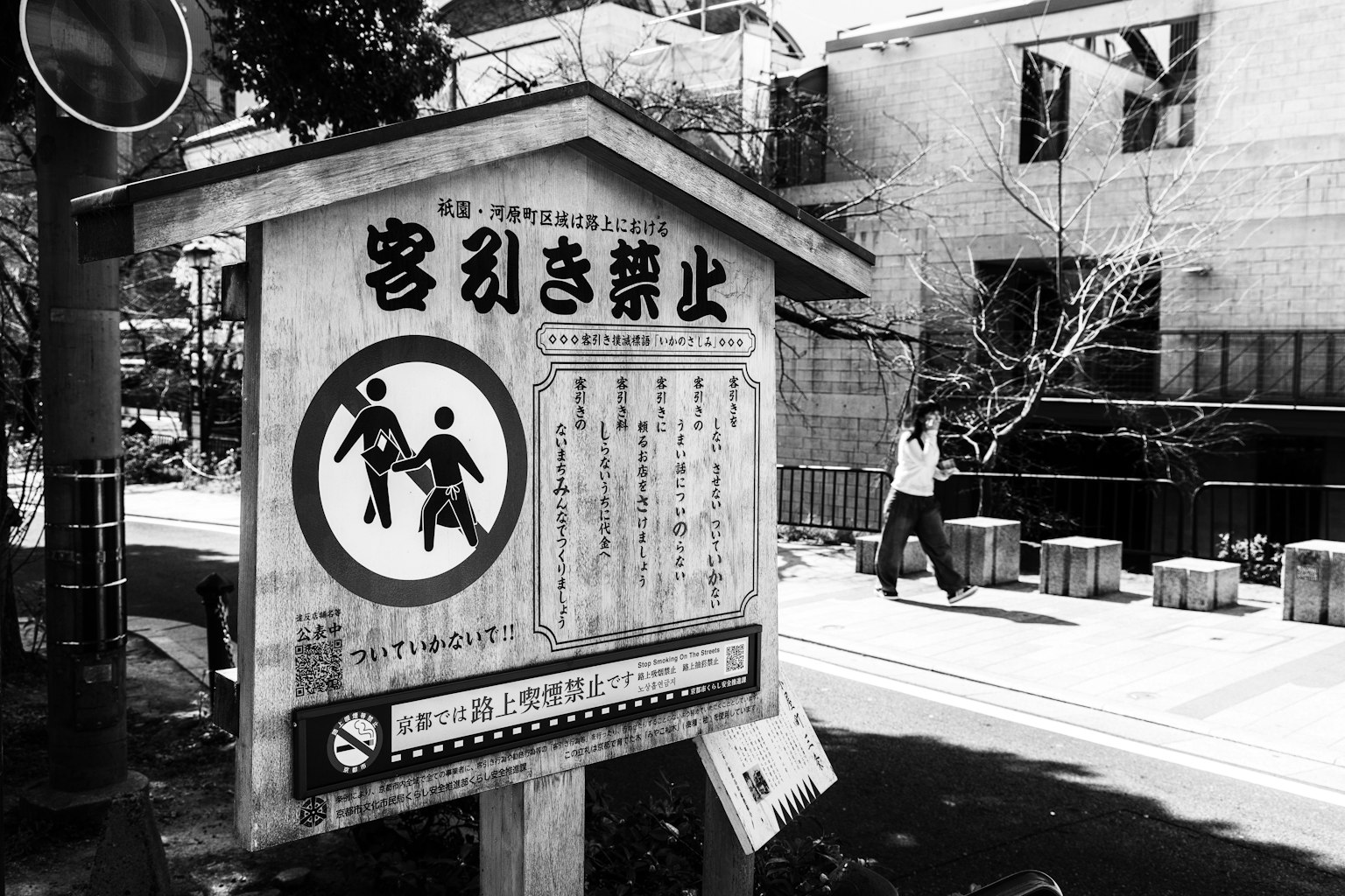 黑白街景，包含禁止招攬的標誌和行人