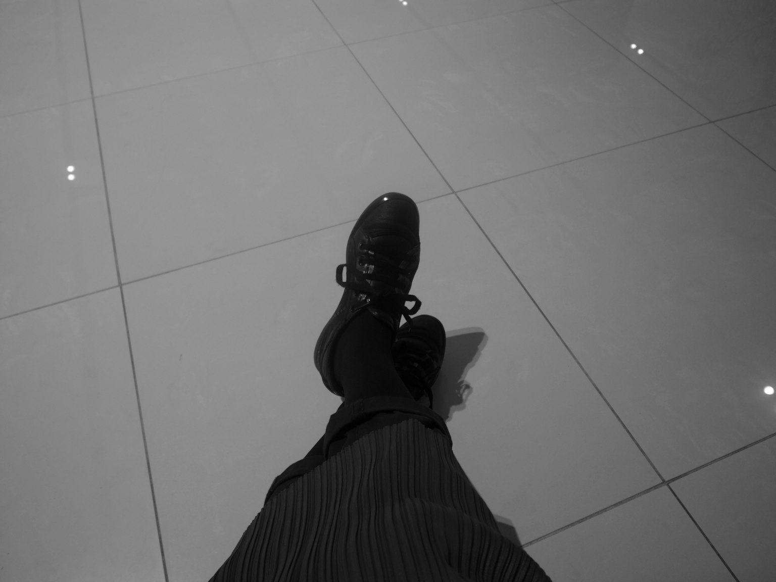 Ein Fuß in einem schwarzen Schuh, der auf einem glänzenden Boden ruht