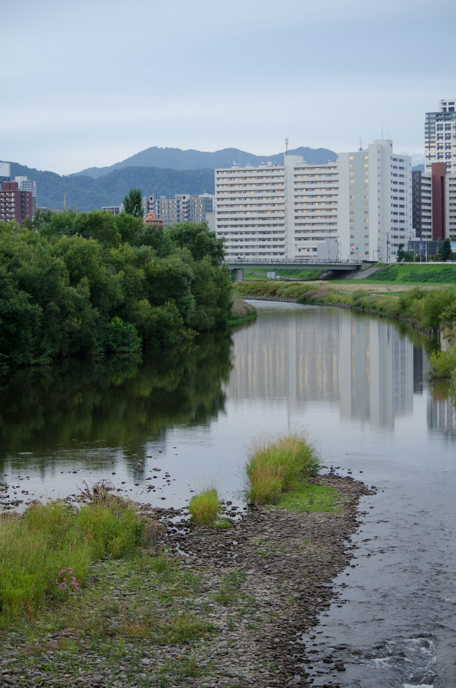 Paysage de rivière avec des montagnes et des reflets de bâtiments de grande hauteur