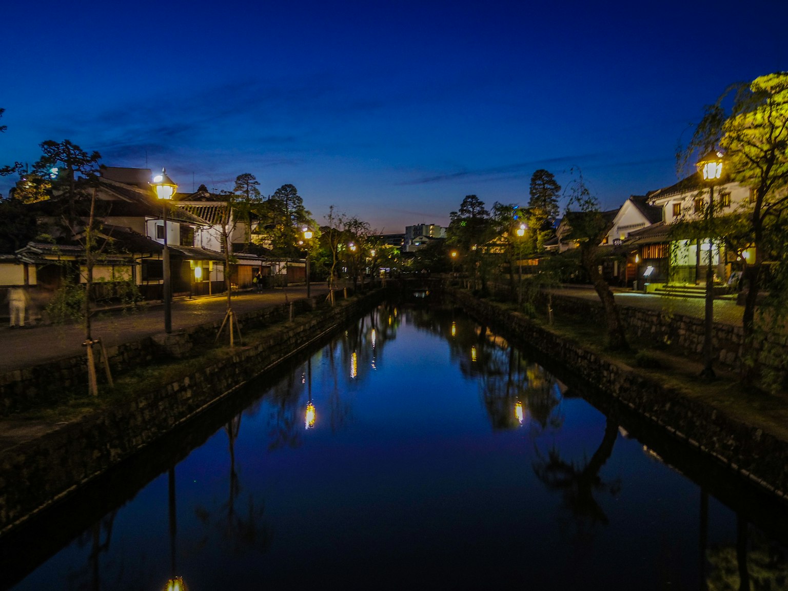 Ville paisible au bord de la rivière la nuit avec des reflets et des lampadaires