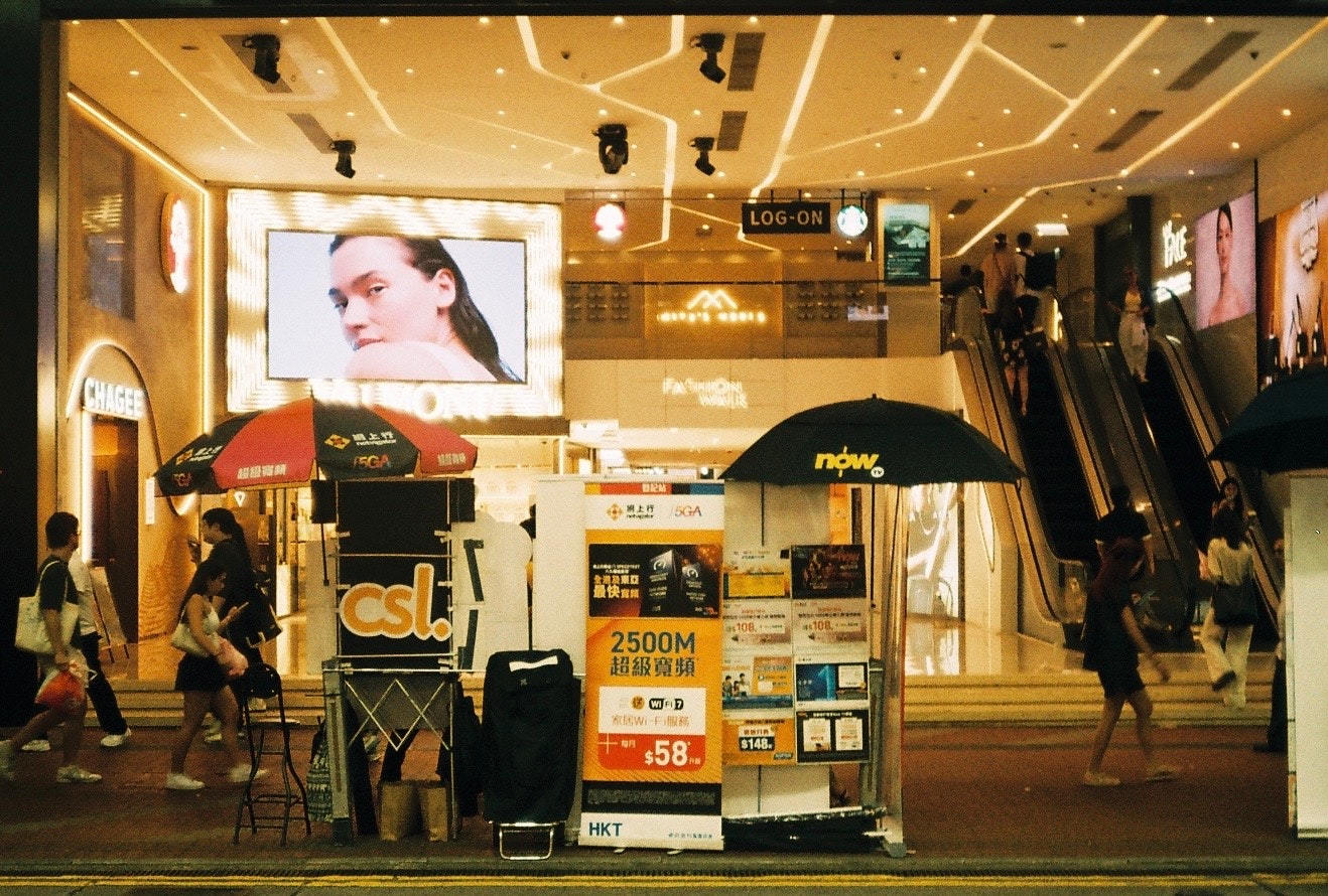 大型スクリーンと屋内の店舗が並ぶショッピングモールの通路