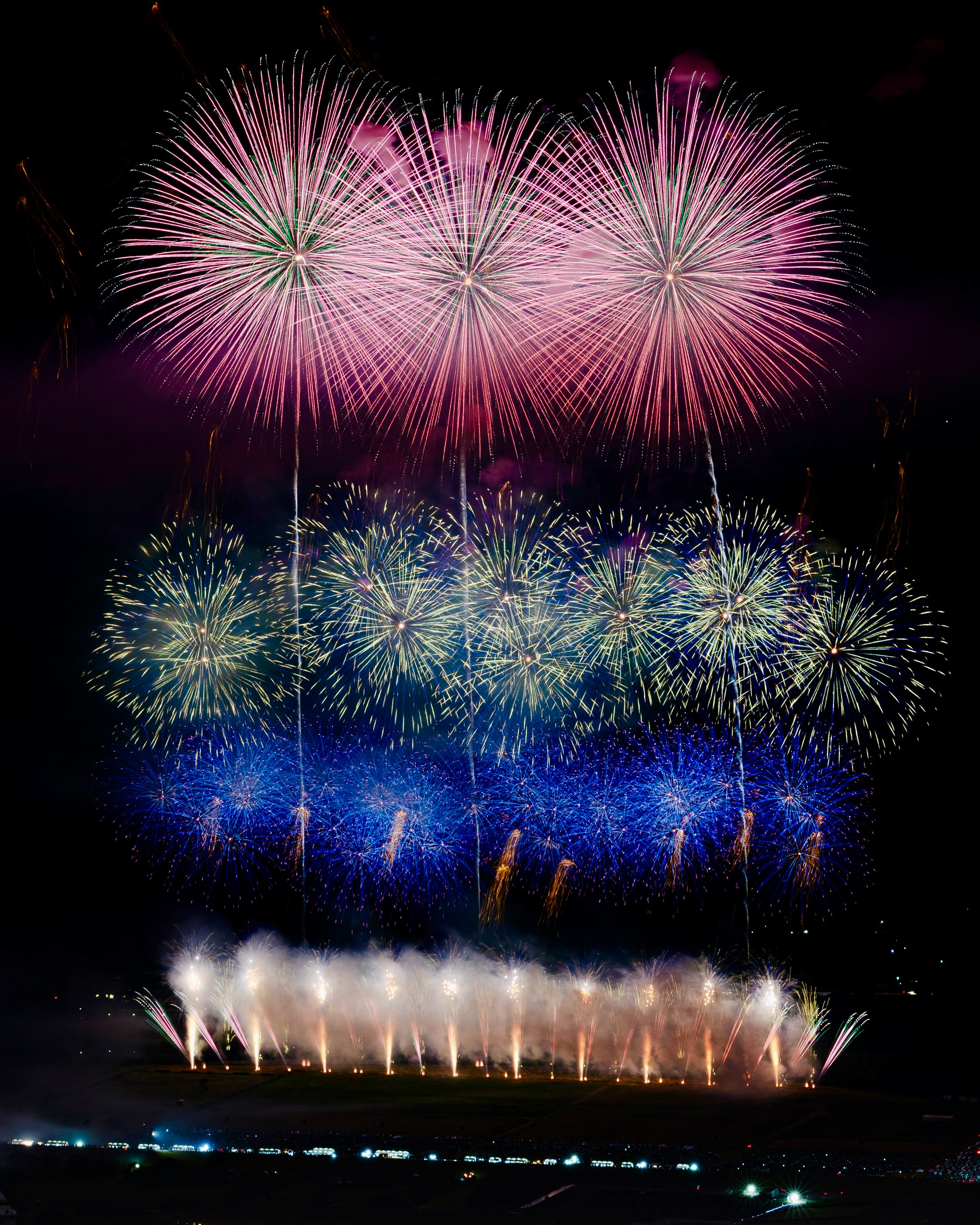 夜空に広がる色とりどりの花火と観客のシルエット