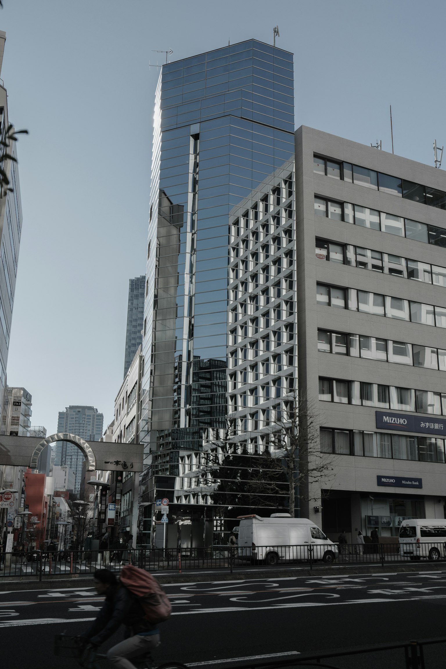 Photo of skyscrapers and cityscape with a person riding a bicycle across the street