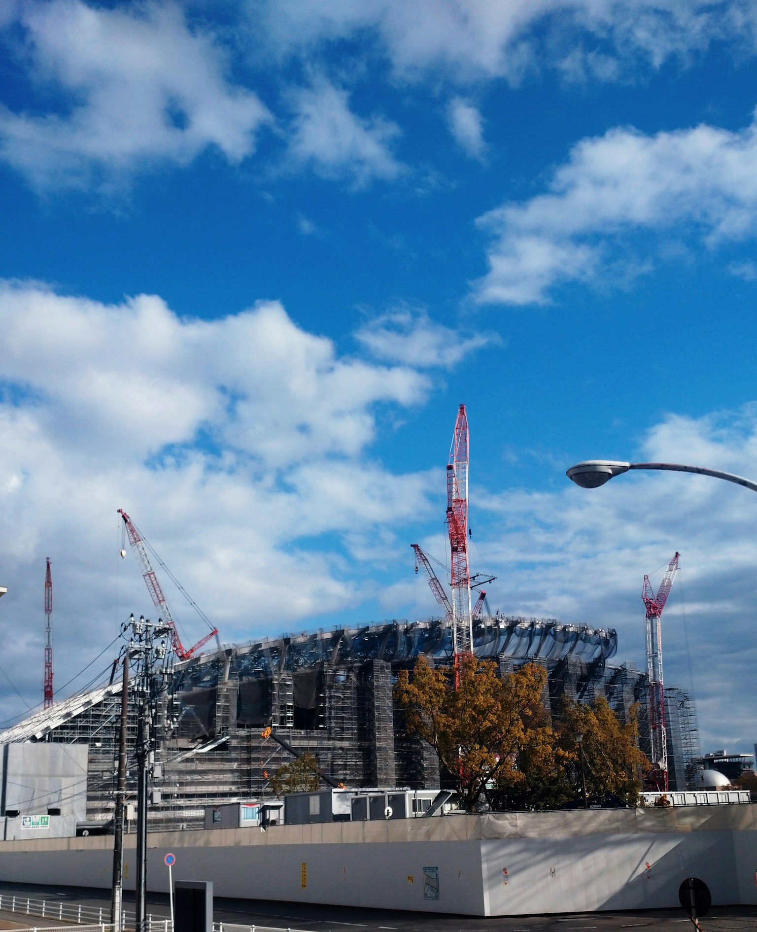 Construction site of a stadium under a blue sky with cranes