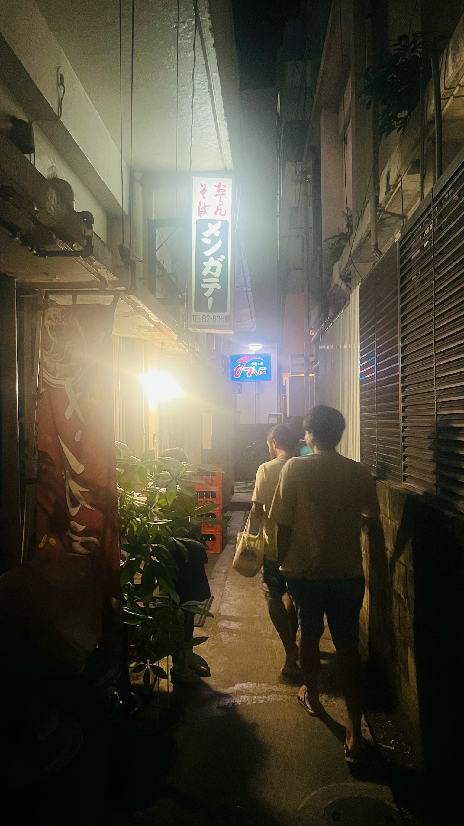 在昏暗小巷中行走的人與霓虹招牌