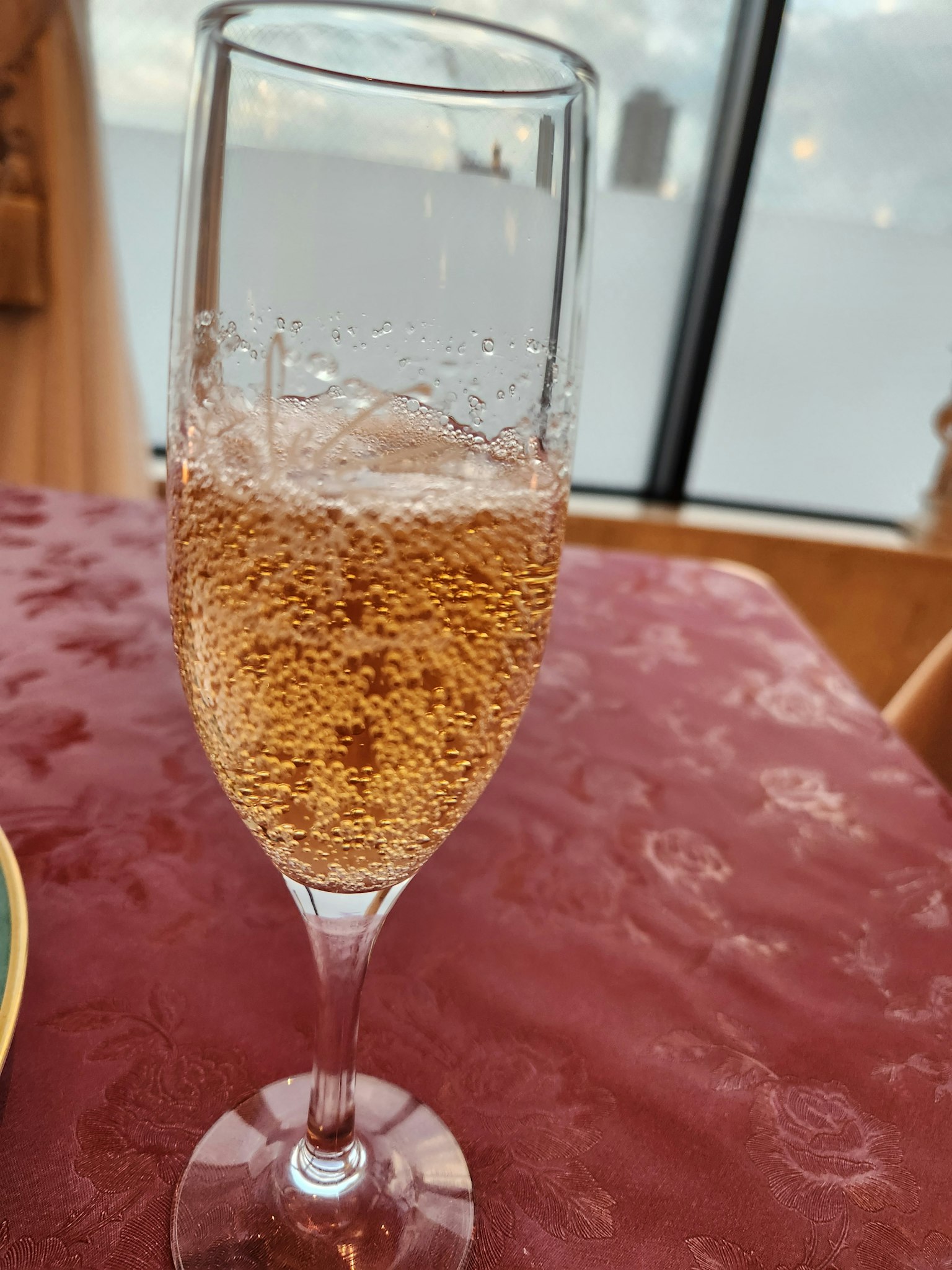Copa de flauta llena de vino espumoso y mantel rojo
