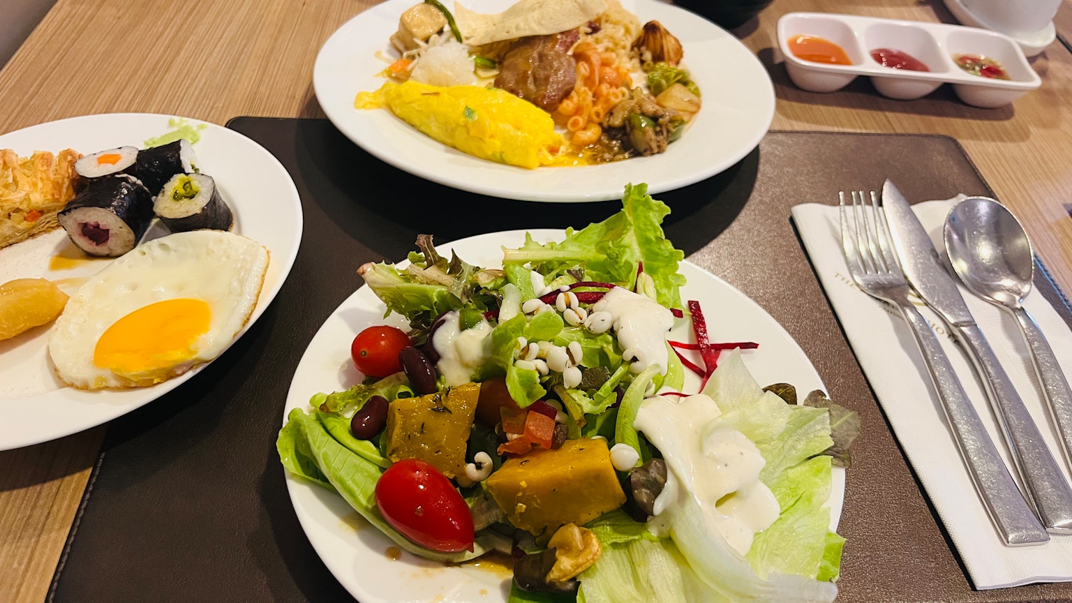 Un plato de comida con ensalada, sushi, plato de huevo y pasta