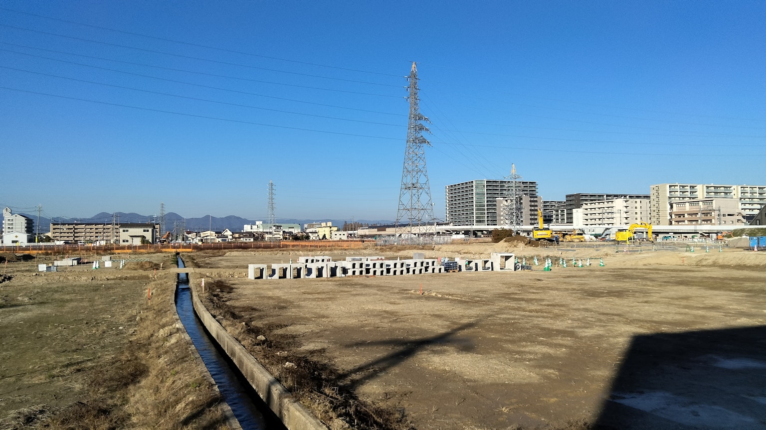 Paesaggio di cantiere con cielo azzurro che mostra una torre radio e edifici