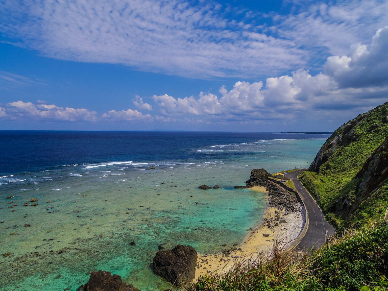 Curved road along a coast with blue sea and green hills