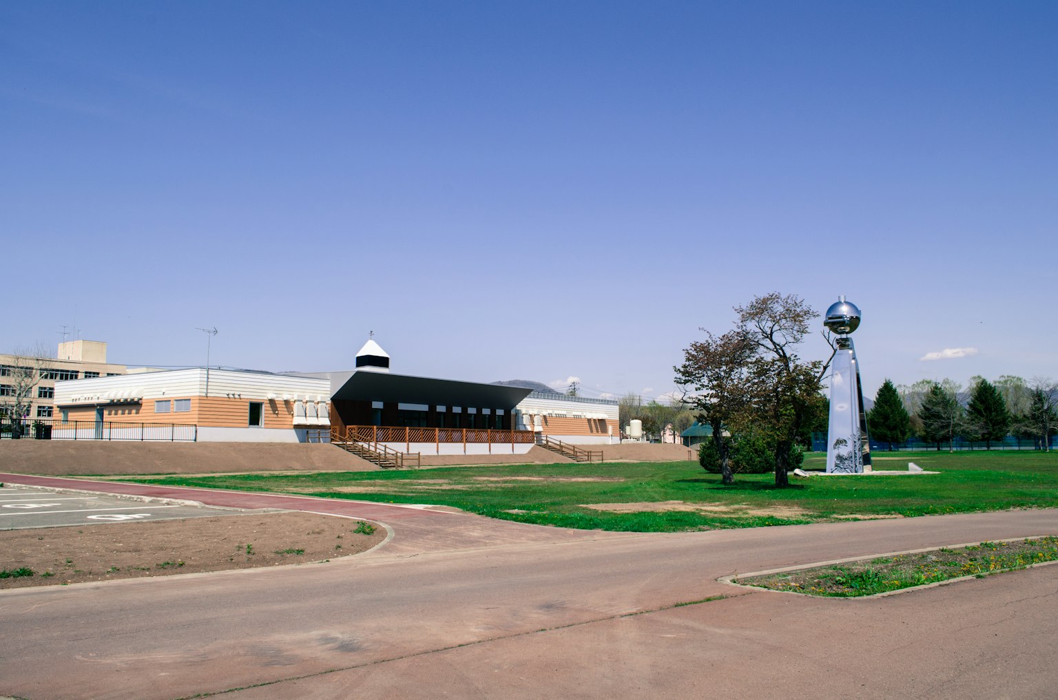 Bâtiment moderne entouré d'un espace vert avec une sculpture