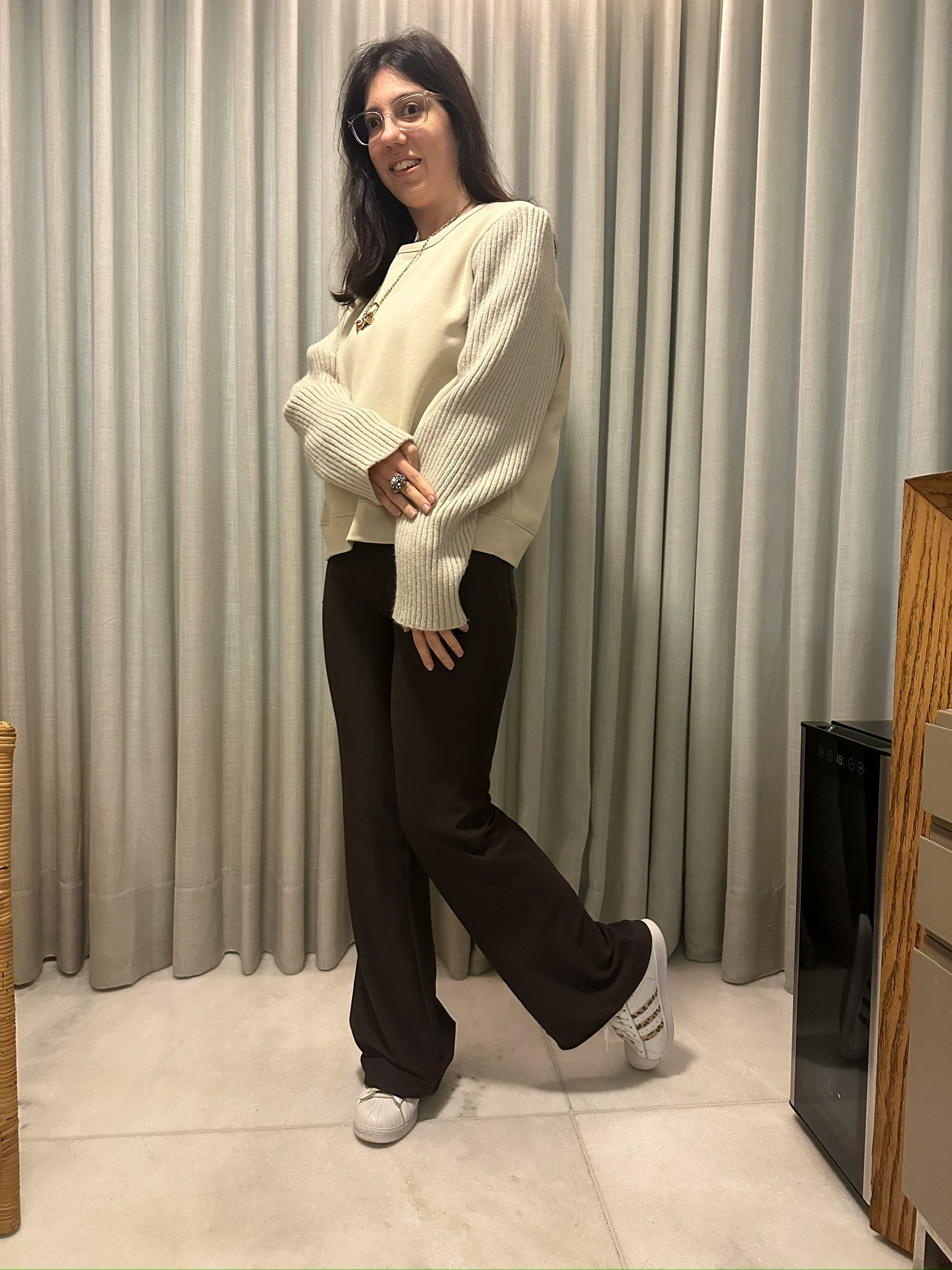 ベージュニットと黒パンツの女性がスタジオでポーズする画像