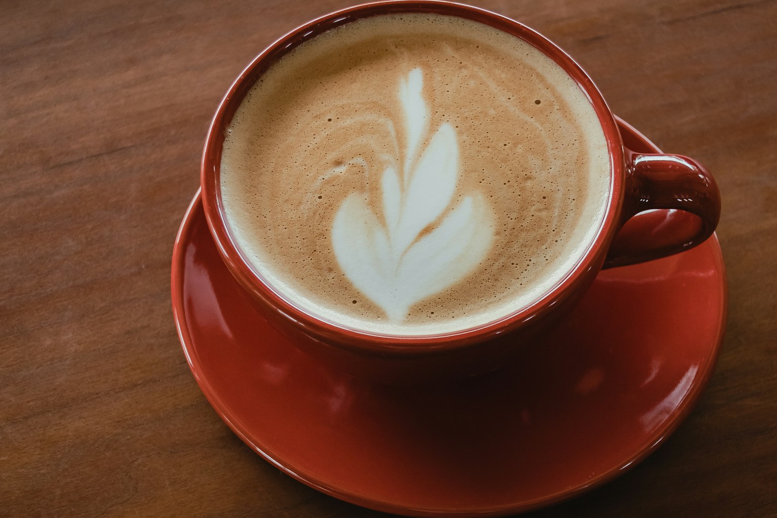 Coffee in a red cup with leaf latte art design