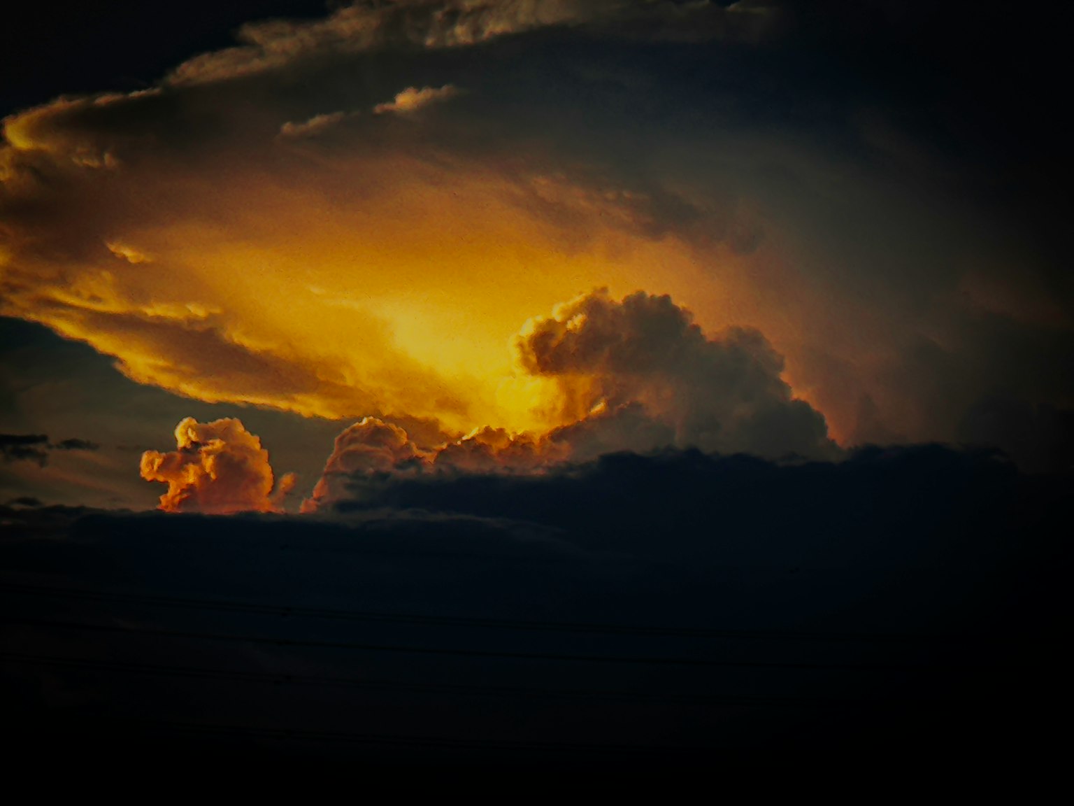 Leuchtende Wolken, erhellt von goldenem Licht gegen einen dunklen Himmel