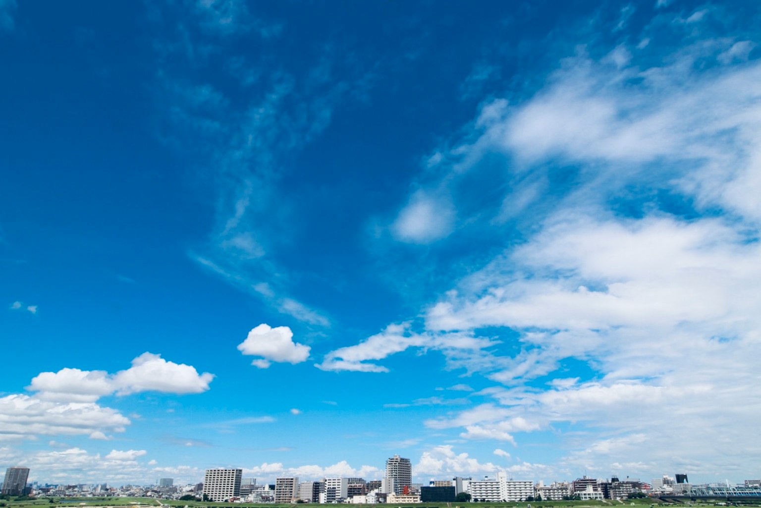 A city skyline under a bright blue sky with fluffy white clouds