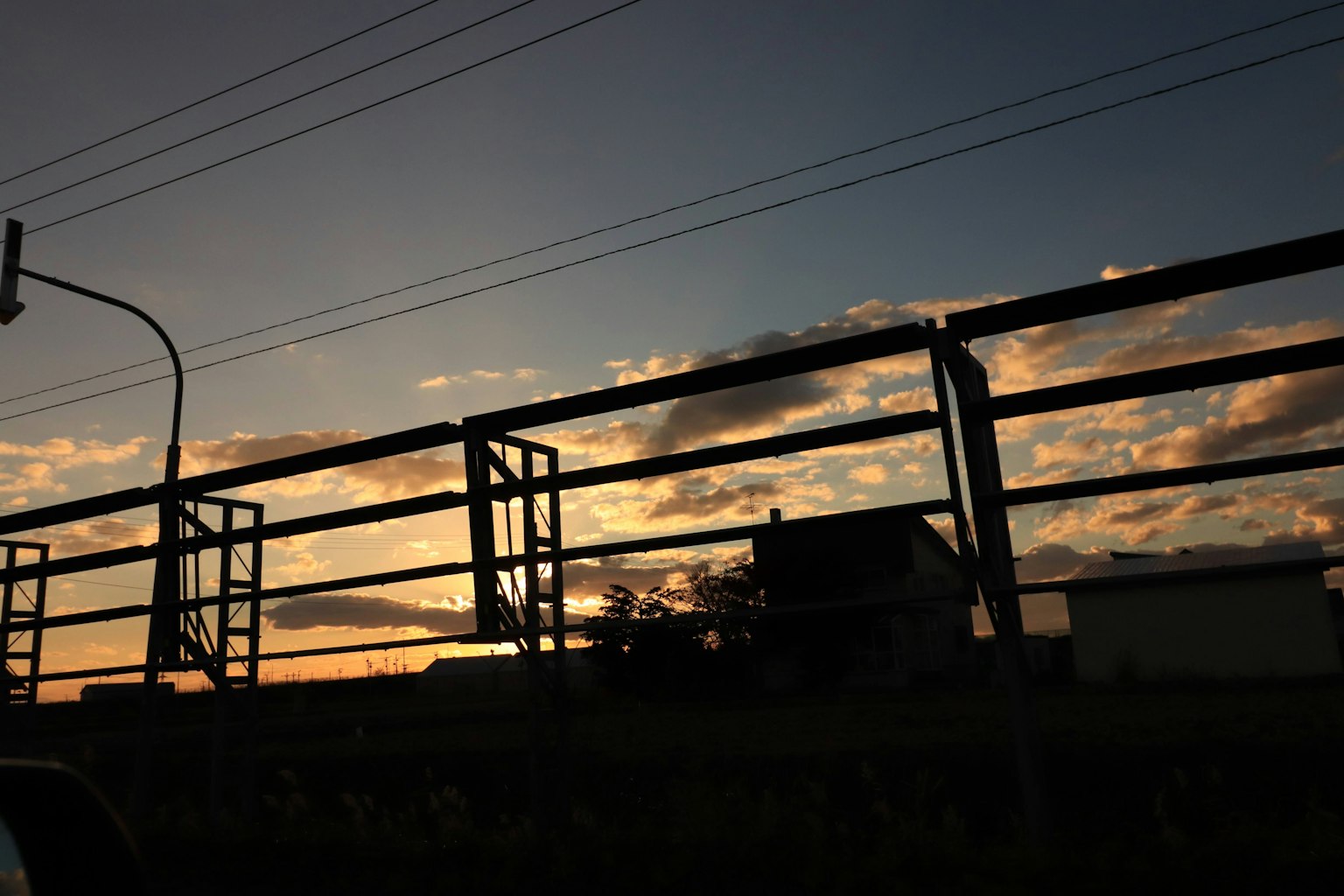 Silhouette eines Hauses und eines Zauns bei Sonnenuntergang