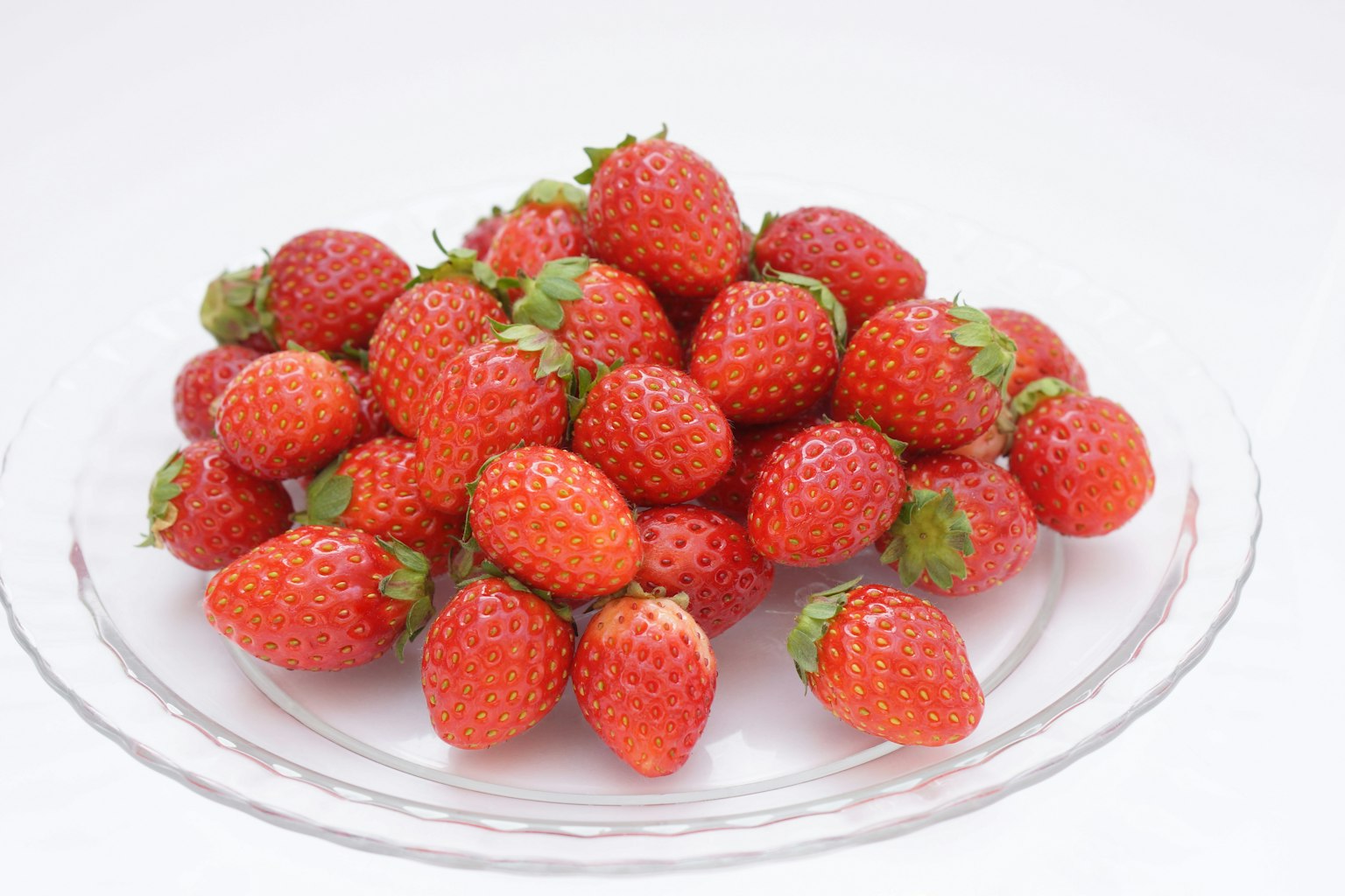 Fraises fraîches empilées sur une assiette en verre transparente