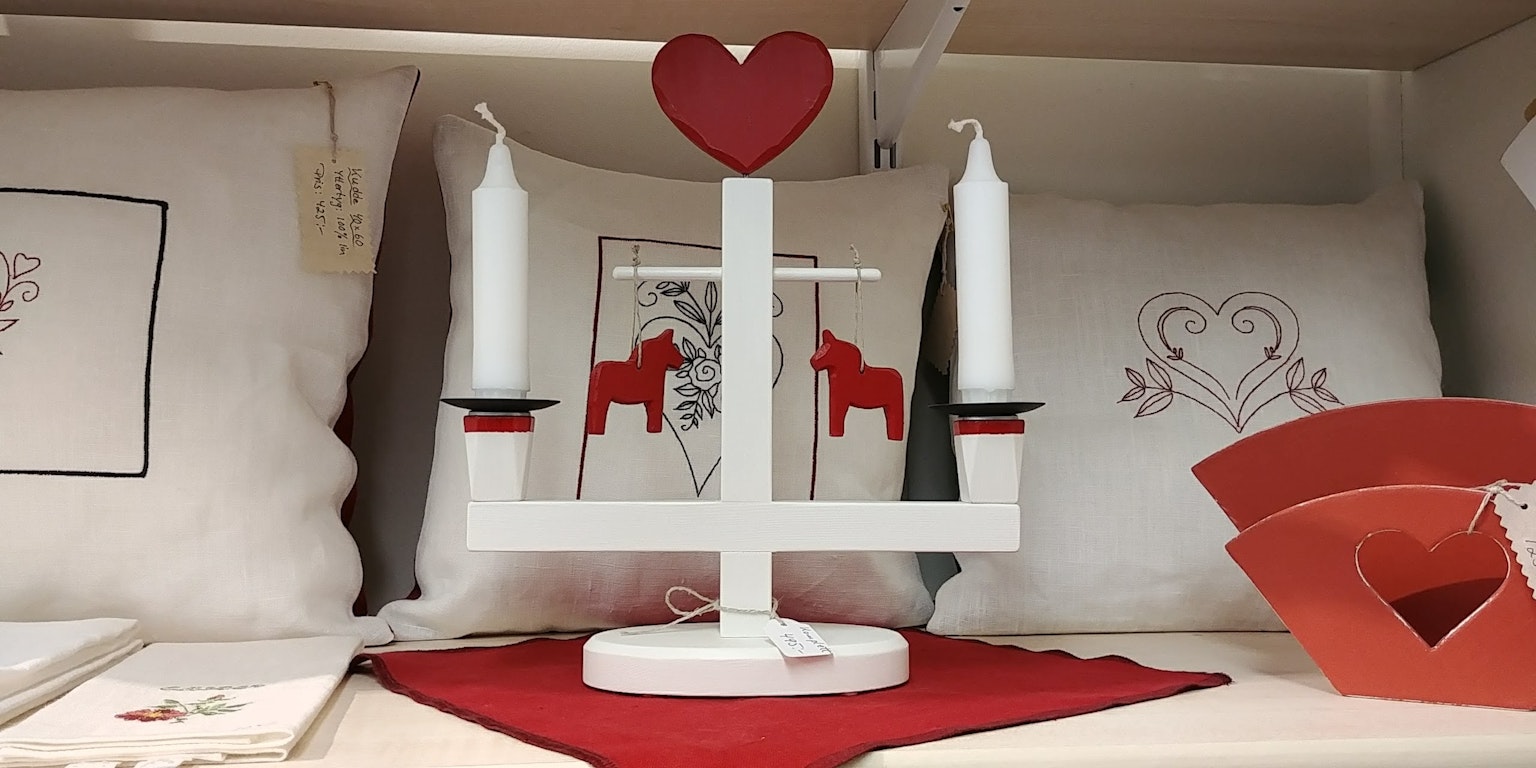 Portavelas con decoración de corazón rojo y dos velas blancas con pequeños caballos rojos
