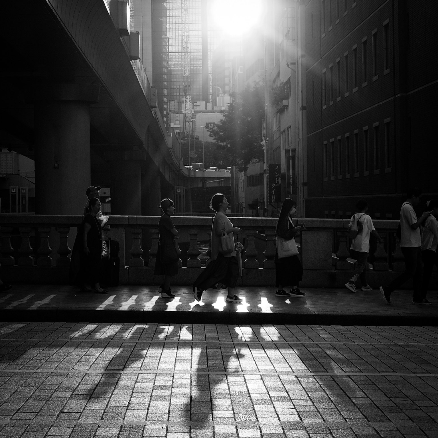 ฉากถนนที่มีผู้คนเดินแสงแดดส่องเข้ามาในขาวดำ